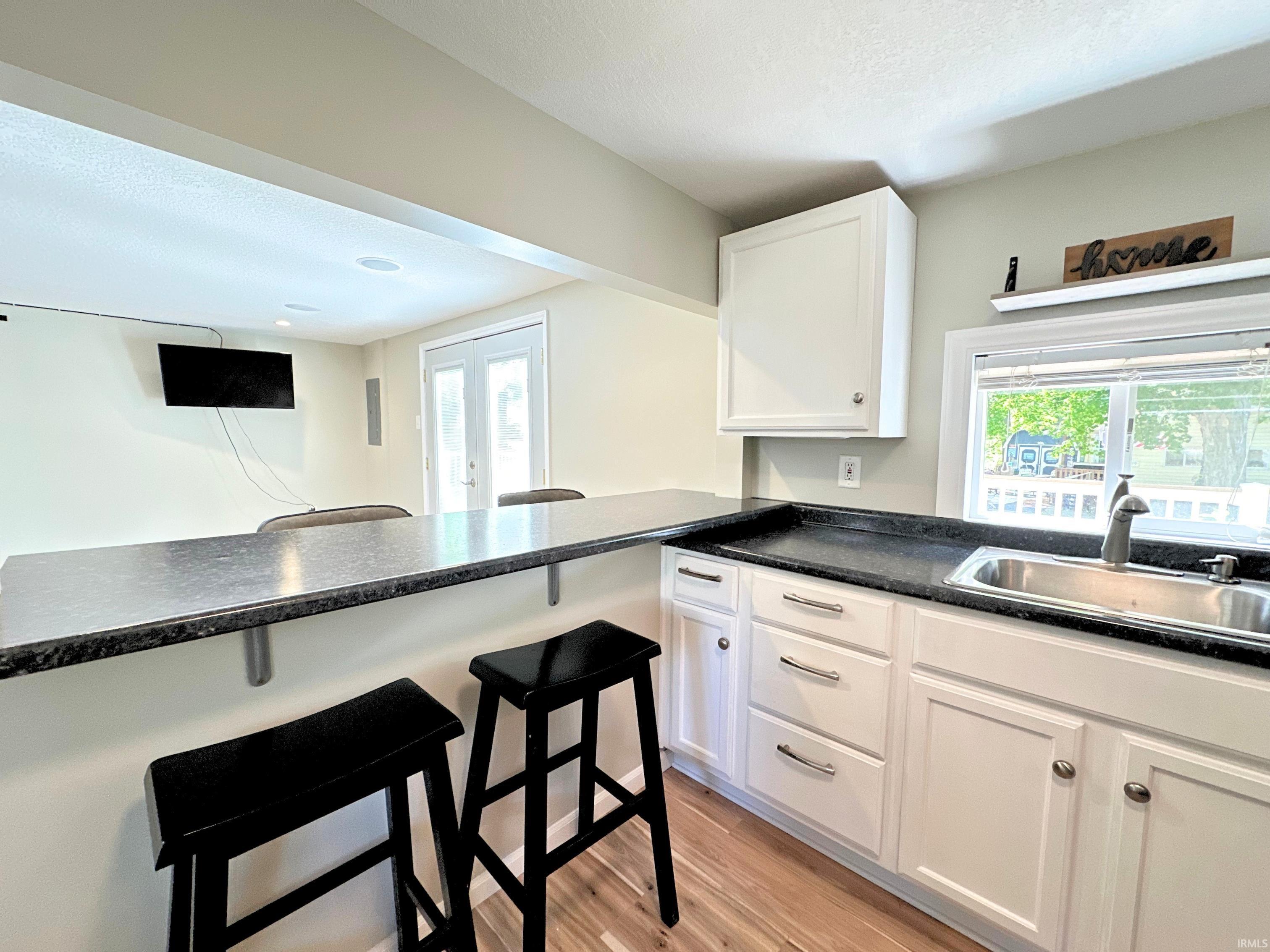 Kitchen area with breakfast bar! This kitchen features newer white cabinetry with brushed nickel hardware, a dark countertop, and a stainless steel sink with a high-arc faucet. Enjoy newer flat-top electric stove and matching stainless steel refrigerator!
