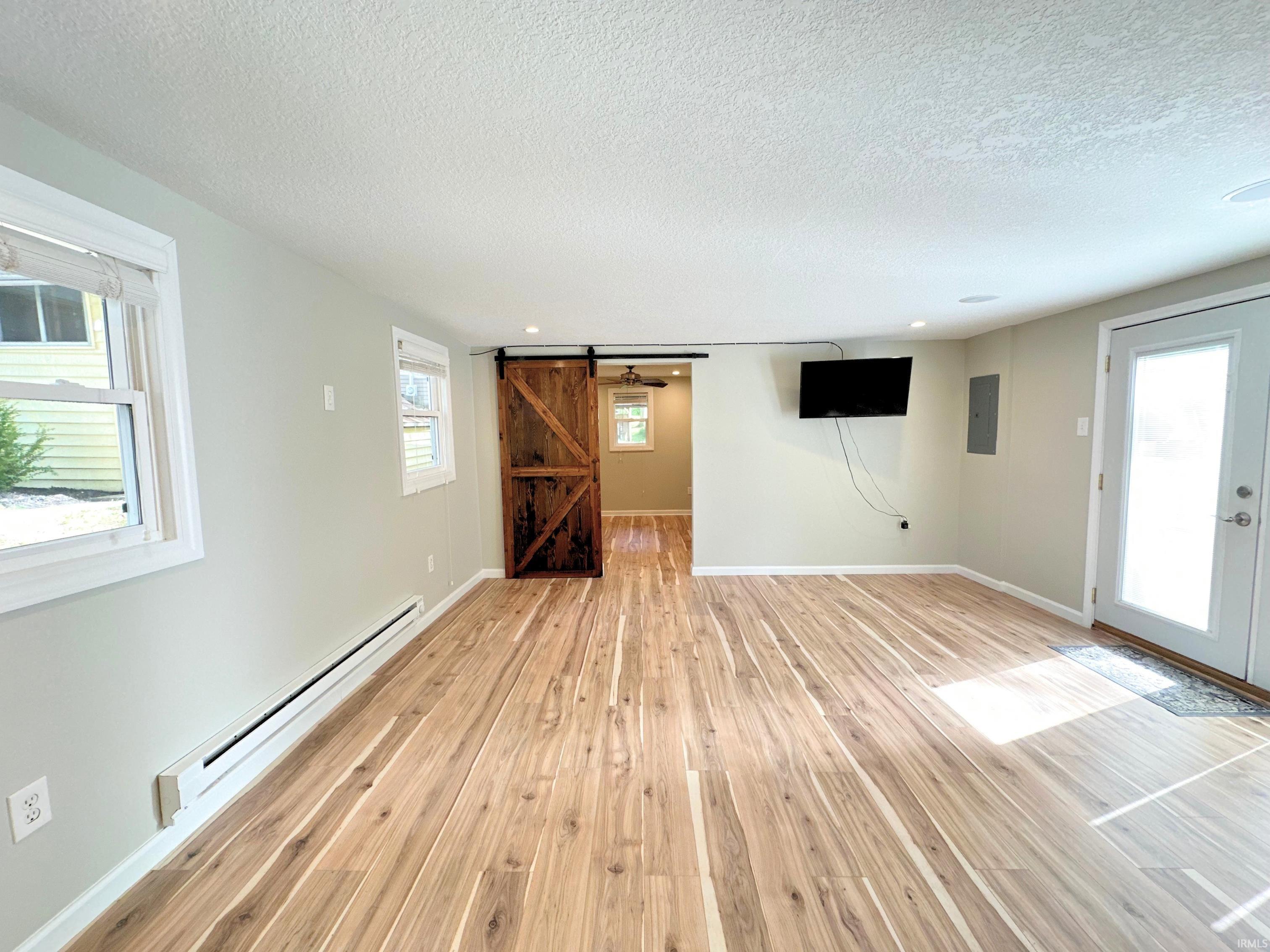 Spacious room with wood-finish flooring, light neutral wall paint, and lots of natural lighting. Entertain guests while creating in the kitchen.