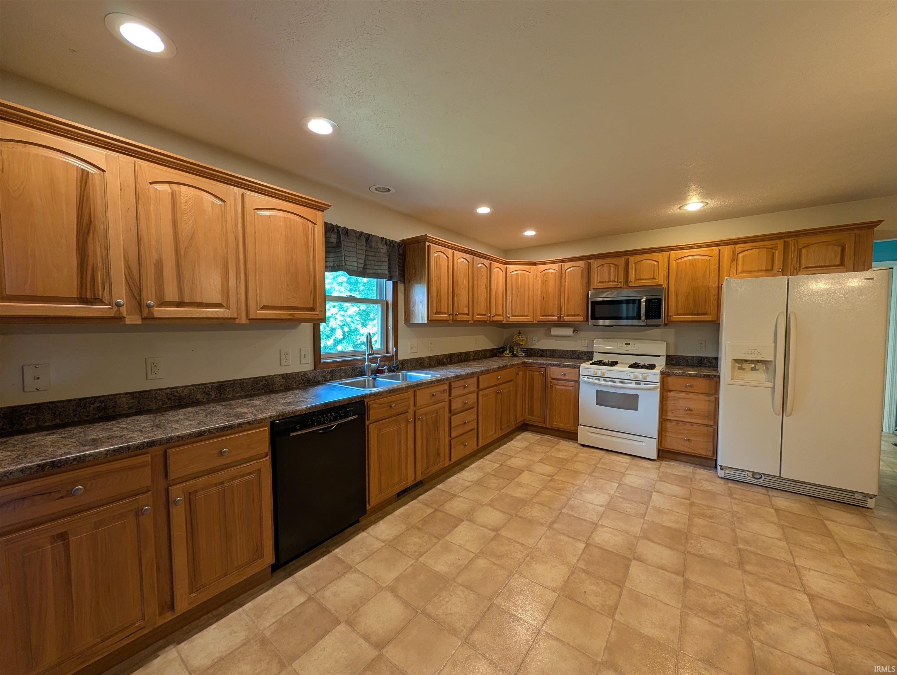 Kitchen featuring extensive wood cabinetry, patterned laminate countertops, and tile-look flooring