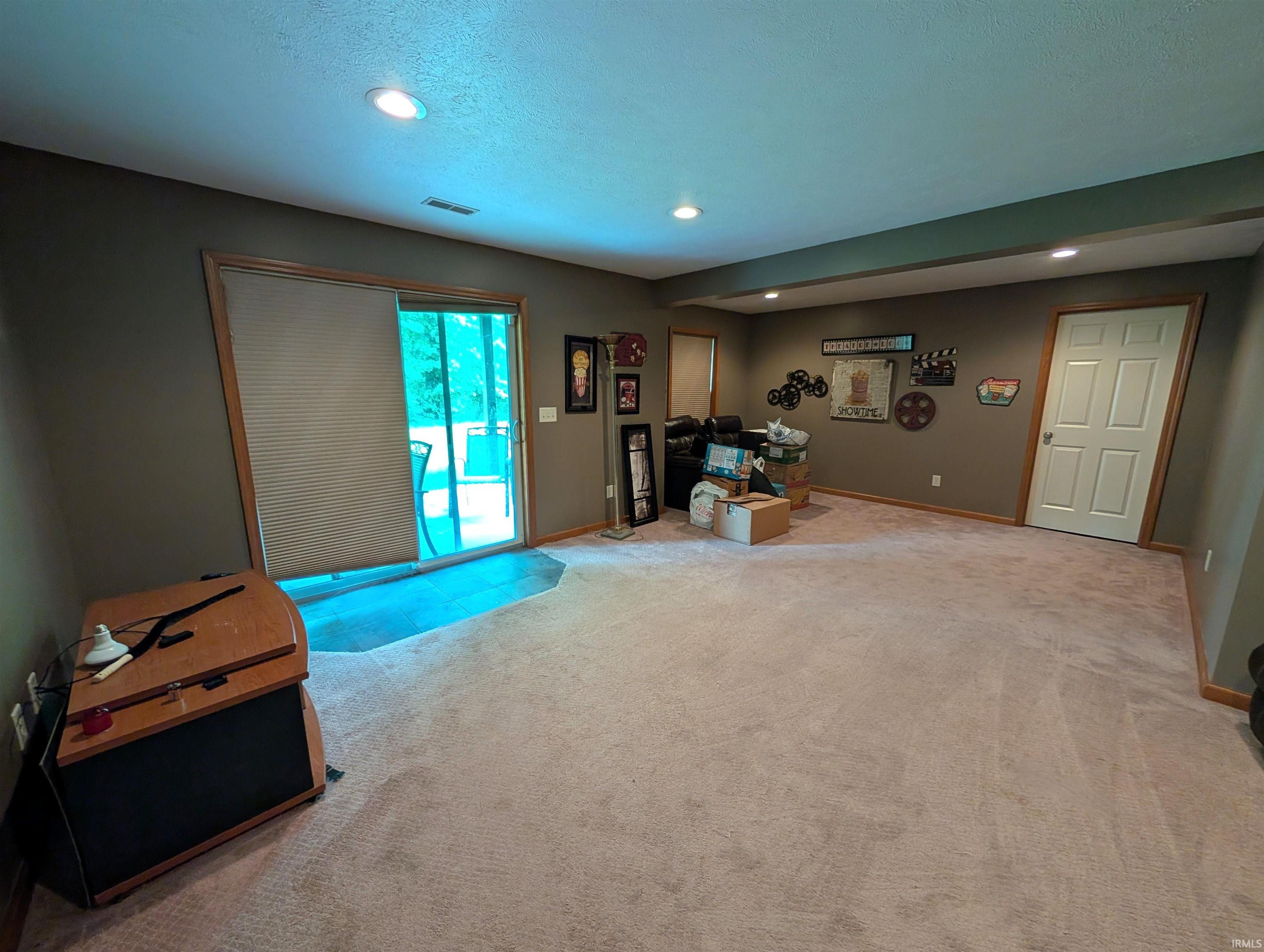 Spacious interior featuring neutral carpeting, recessed lighting, and a sliding glass door with blinds leading to an exterior area