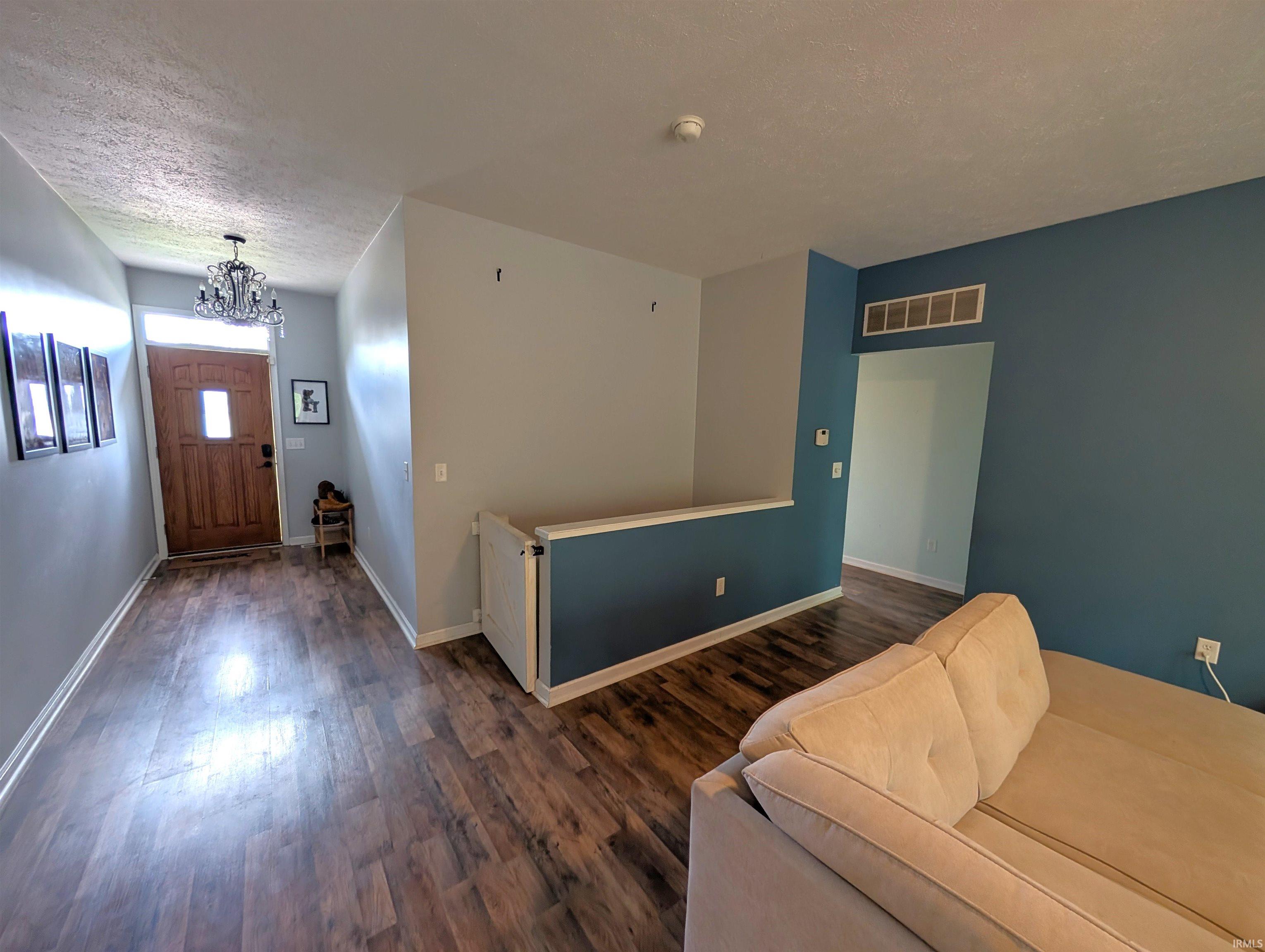 Entryway featuring wood-finish flooring, a wood-panel front door with a transom window, and a chandelier with faceted accents