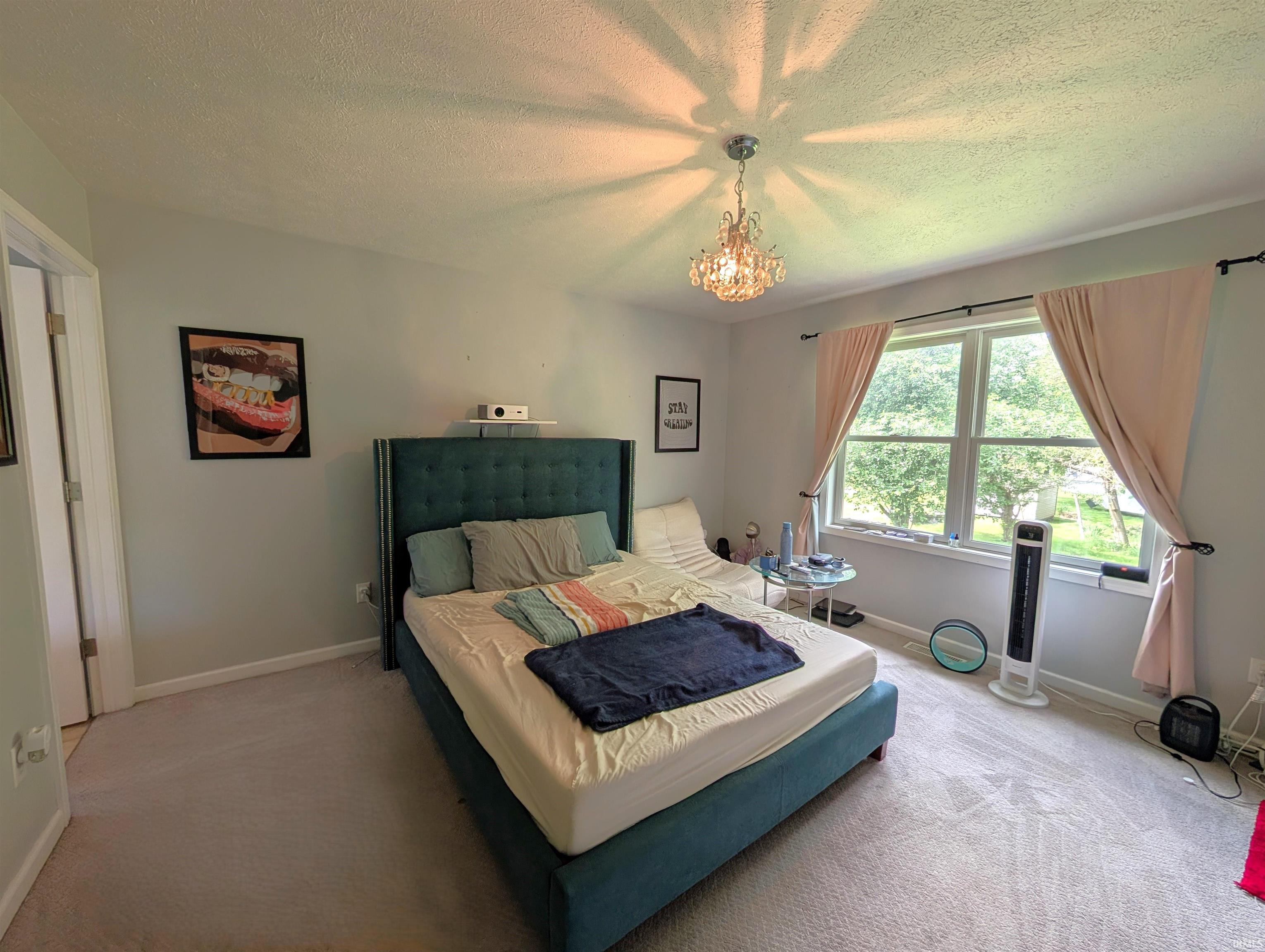 Carpeted room featuring a double window, overhead chandelier, and light-colored walls
