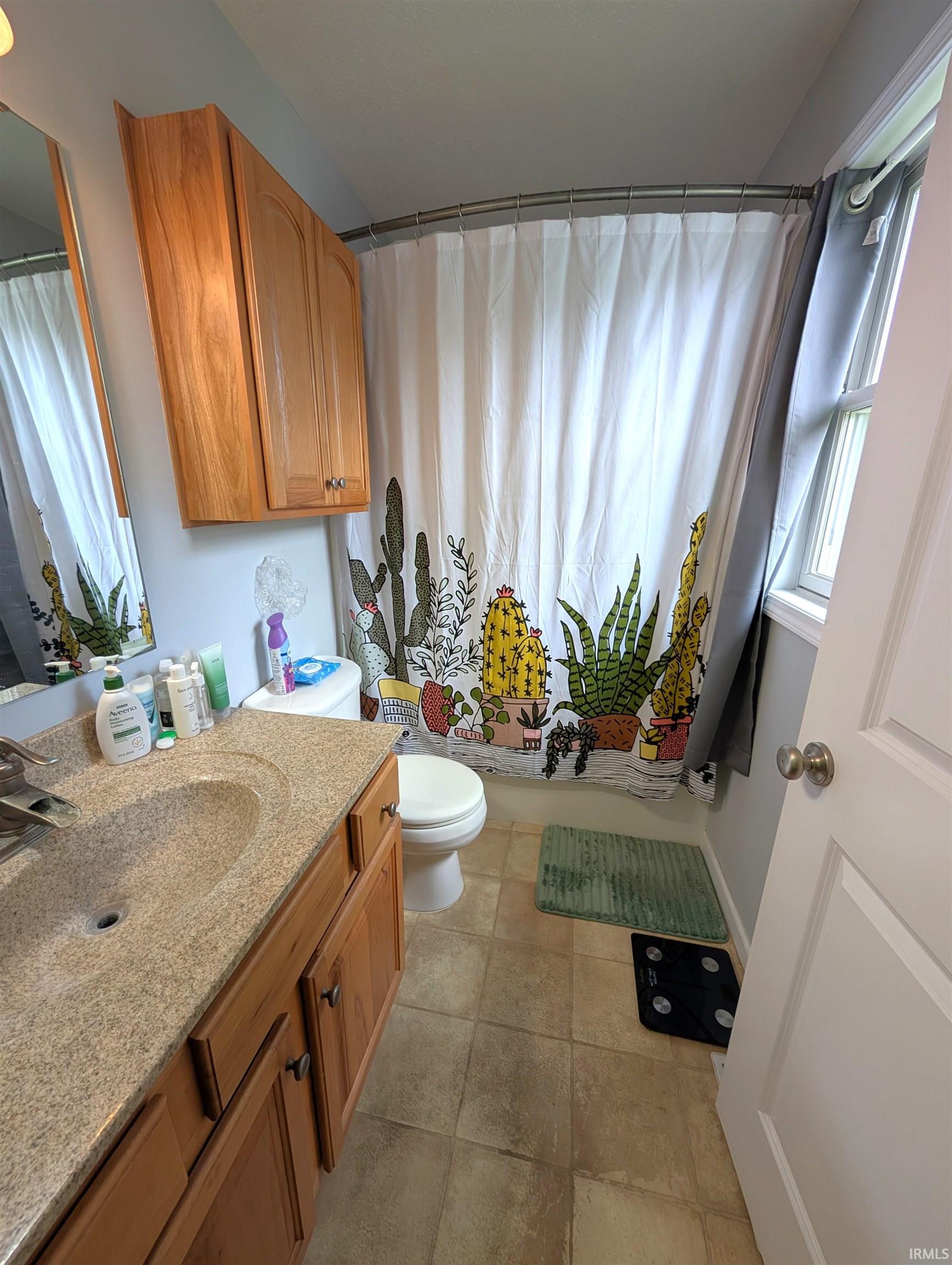Bathroom featuring a vanity with a light-toned countertop, wood-finish cabinetry, and a mirrored medicine cabinet