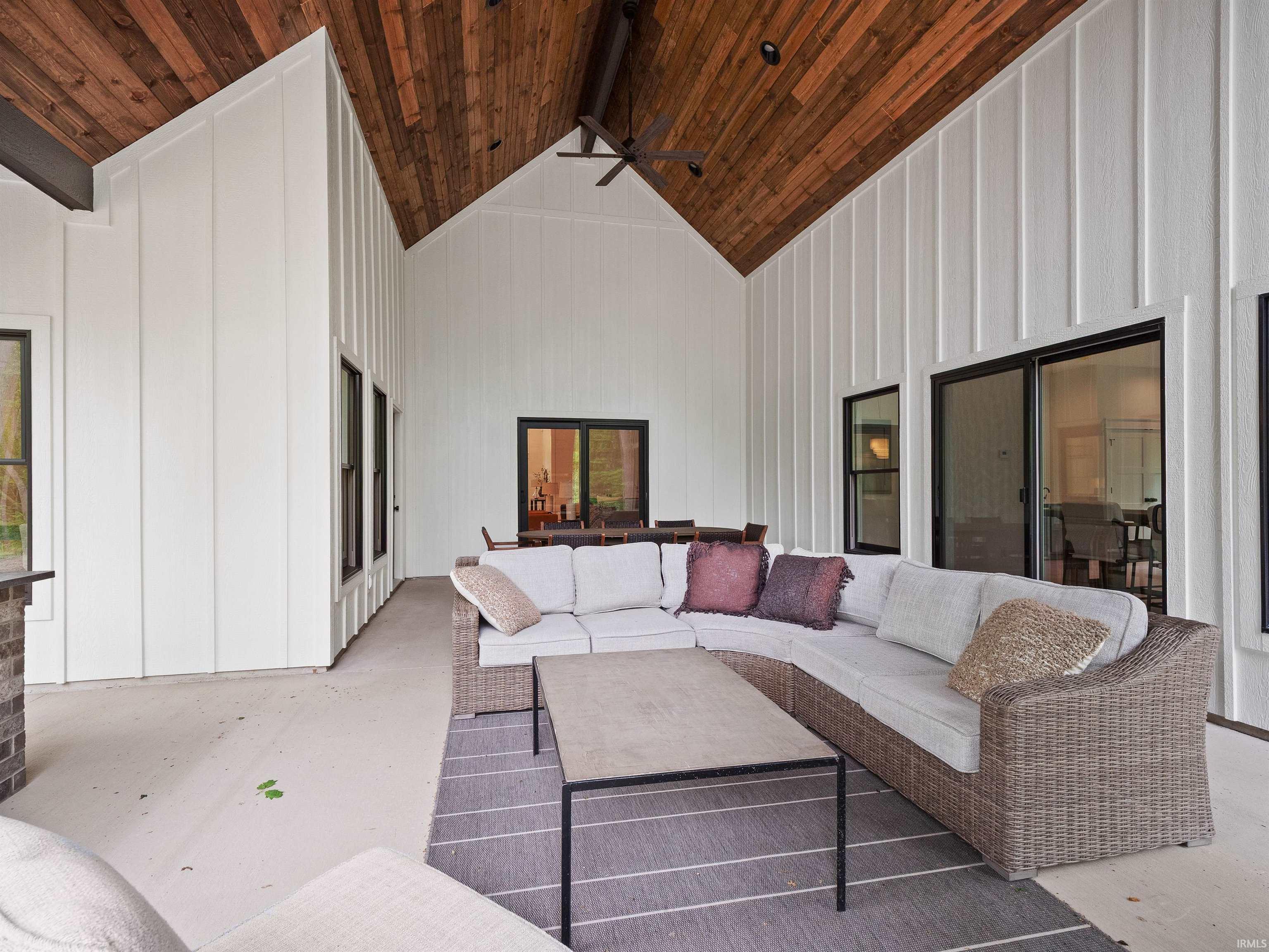 Expansive covered patio featuring a vaulted wood-finish ceiling, board and batten siding, and recessed lighting