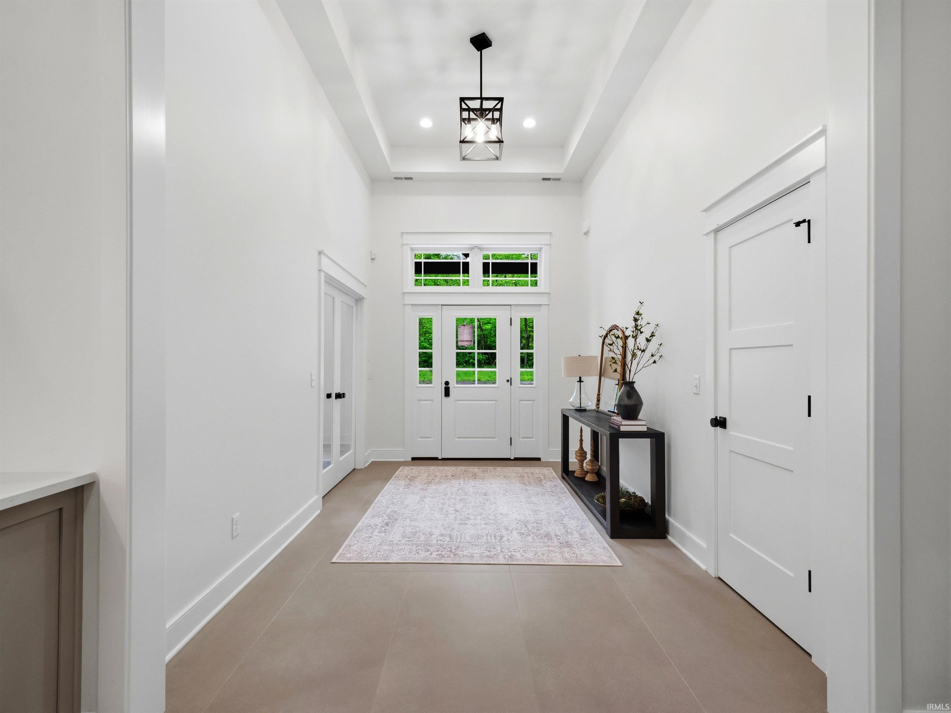Bright entryway featuring a double door with glass panes, transom window, recessed lighting, wood-finish flooring, and a tray ceiling