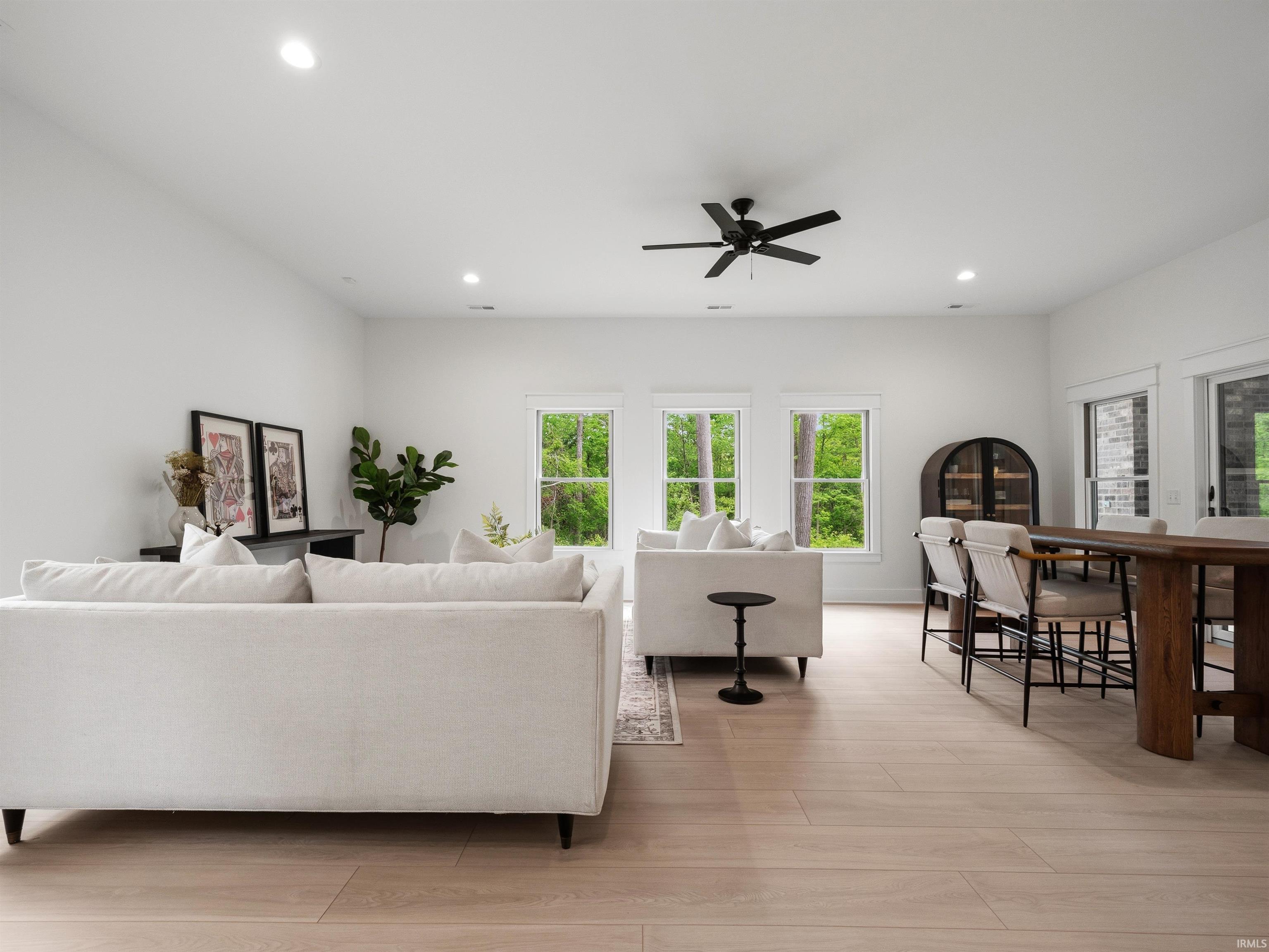 Spacious open-concept living area featuring light wood-finish flooring, recessed lighting, and a modern ceiling fan