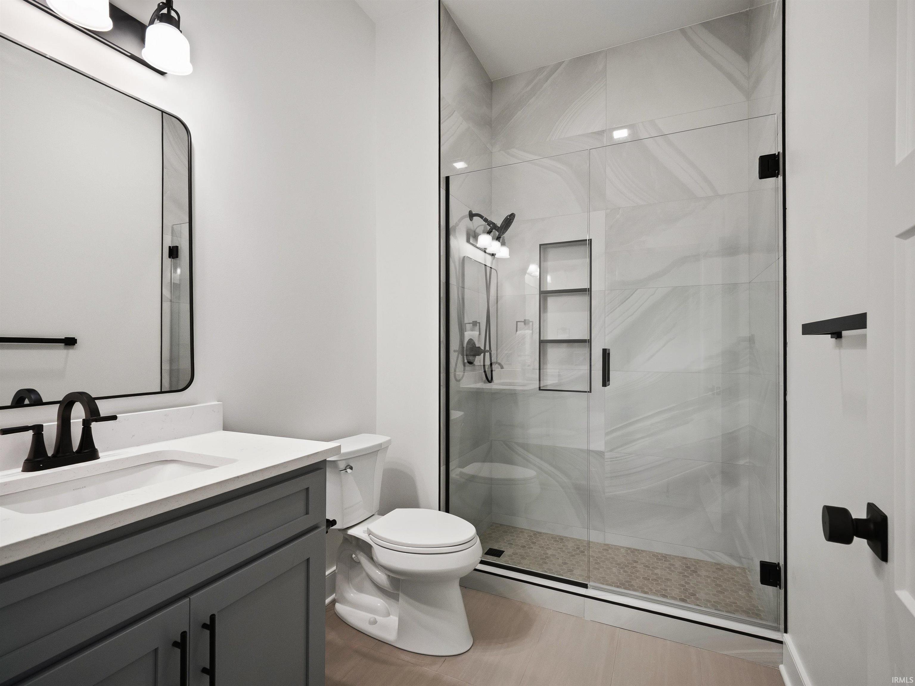 Glass-enclosed shower with tiled walls and built-in shelving