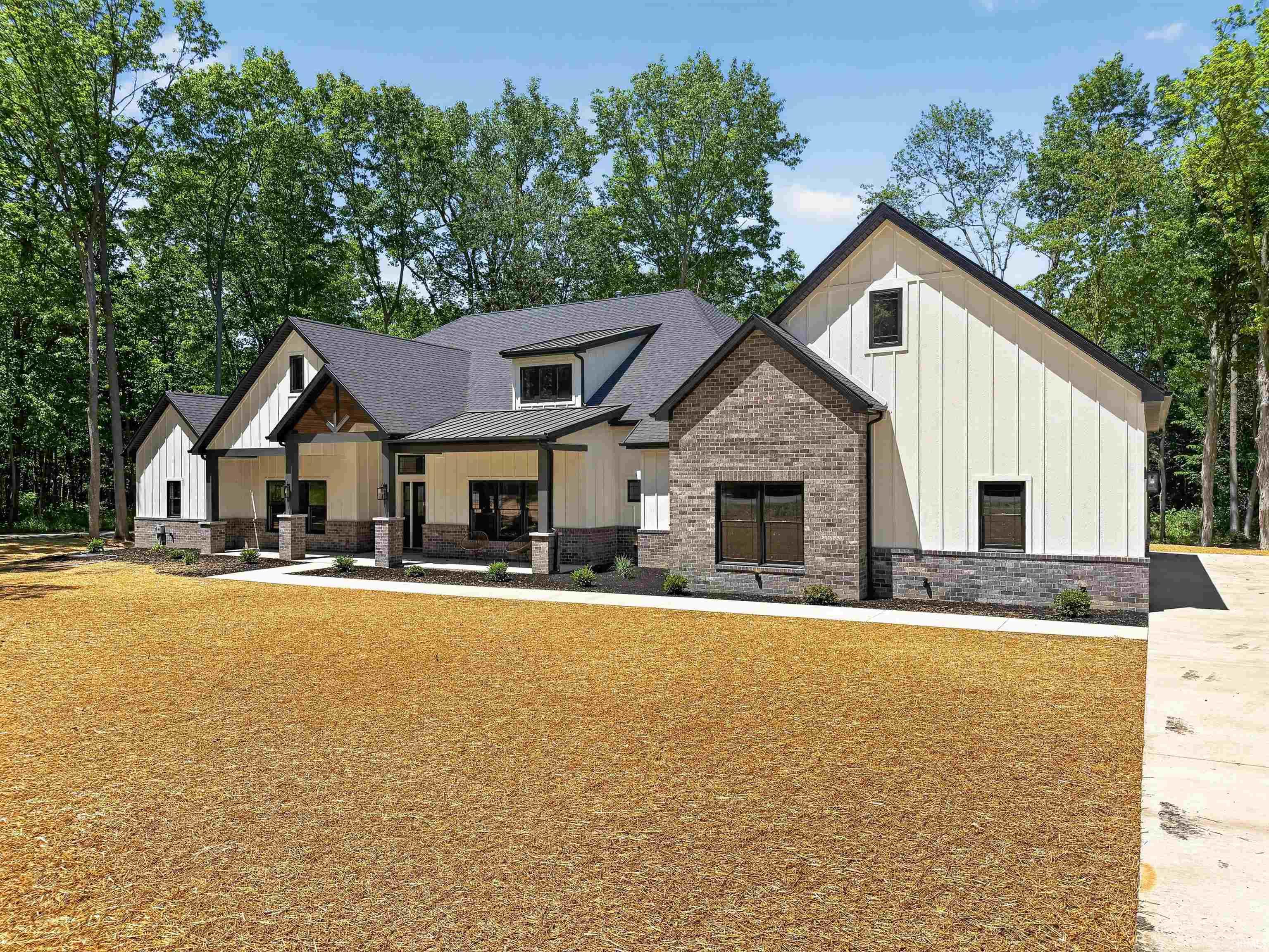 Contemporary-style residence featuring a dark asphalt shingle roof and a combination of white board-and-batten siding and grey brick veneer