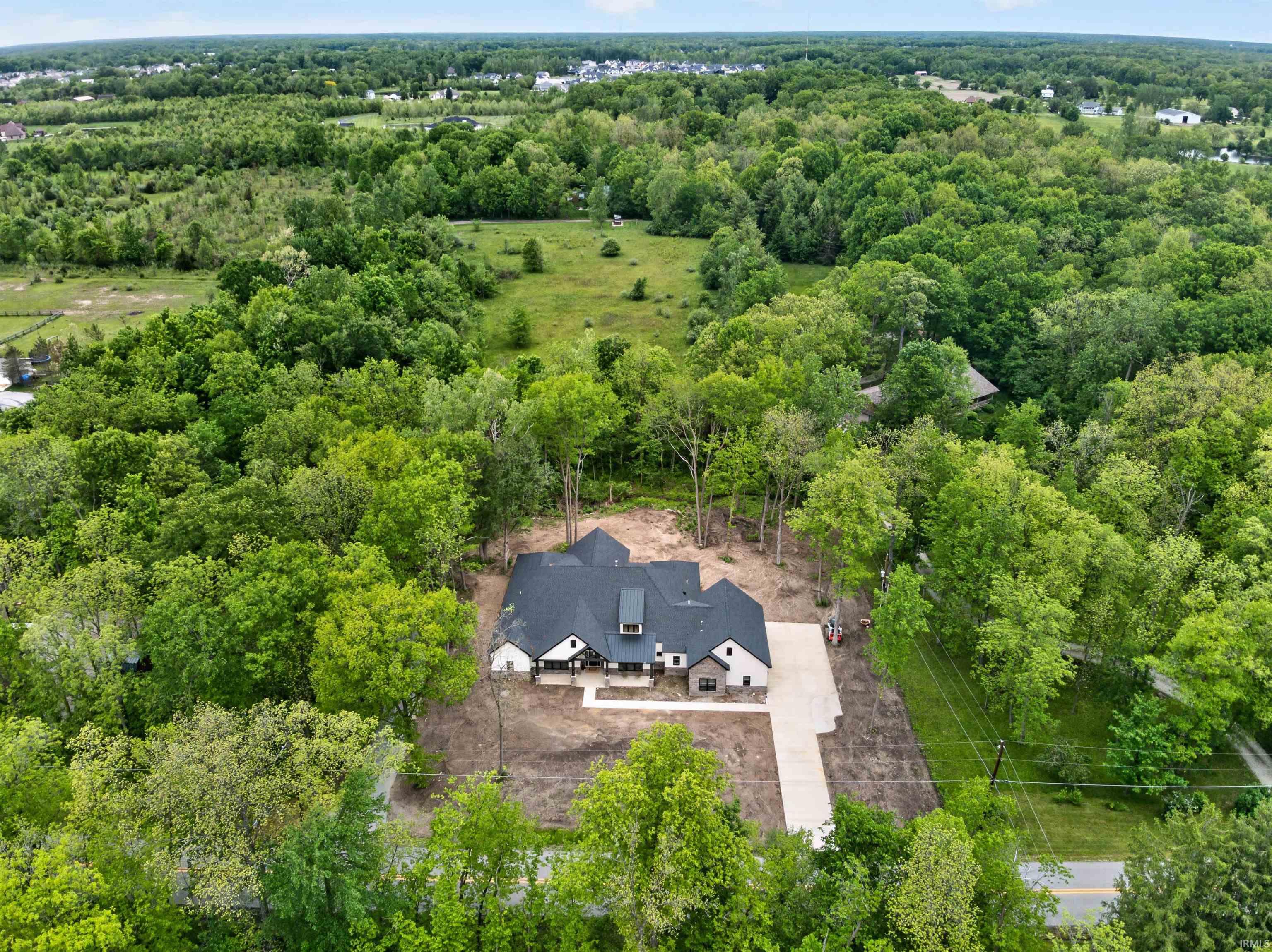 Contemporary residence featuring a dark shingle roof, light-toned siding, and stone accents