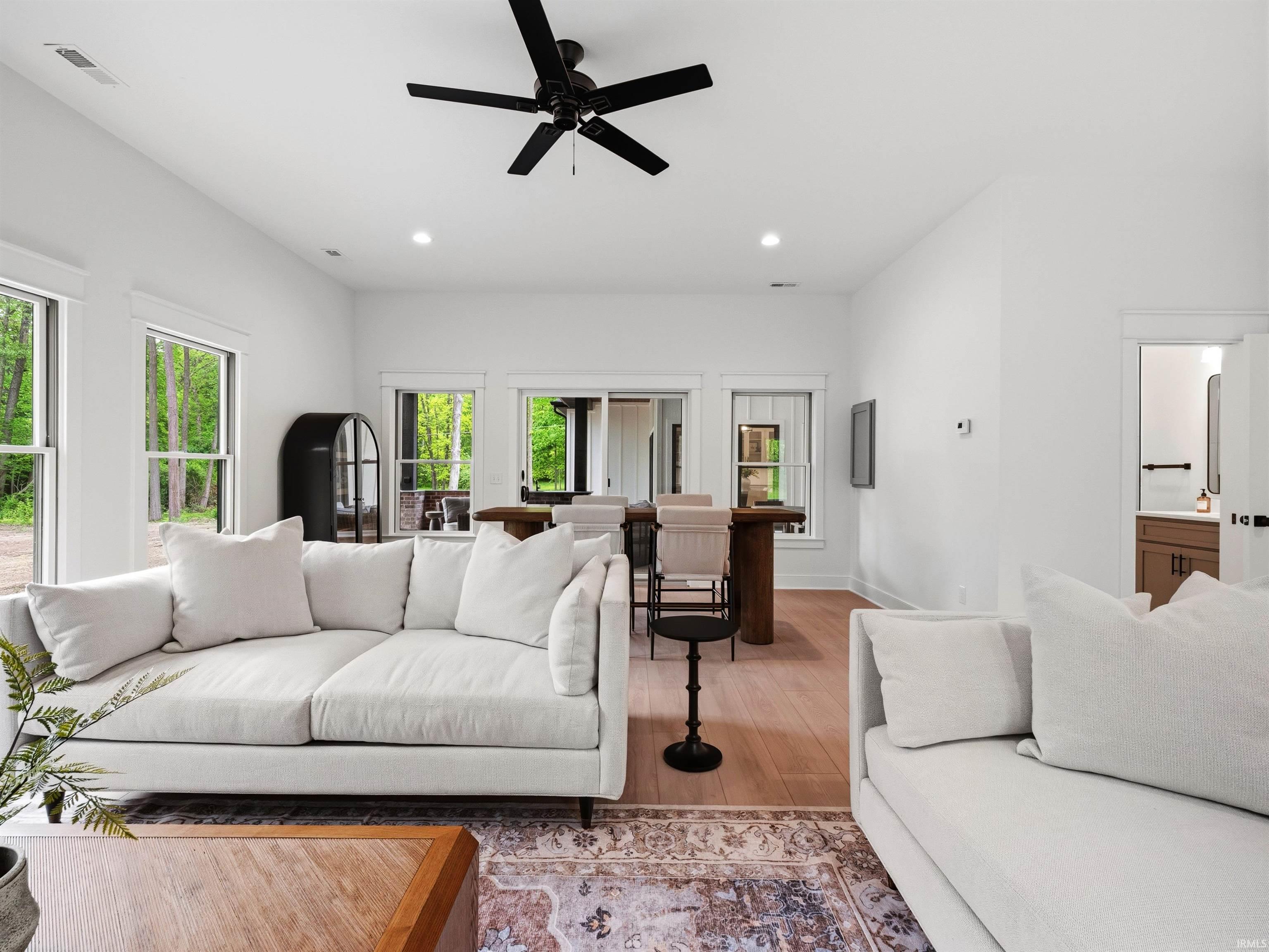 Open-concept living area featuring vaulted ceilings, recessed lighting, a modern black ceiling fan, and light wood-finish flooring