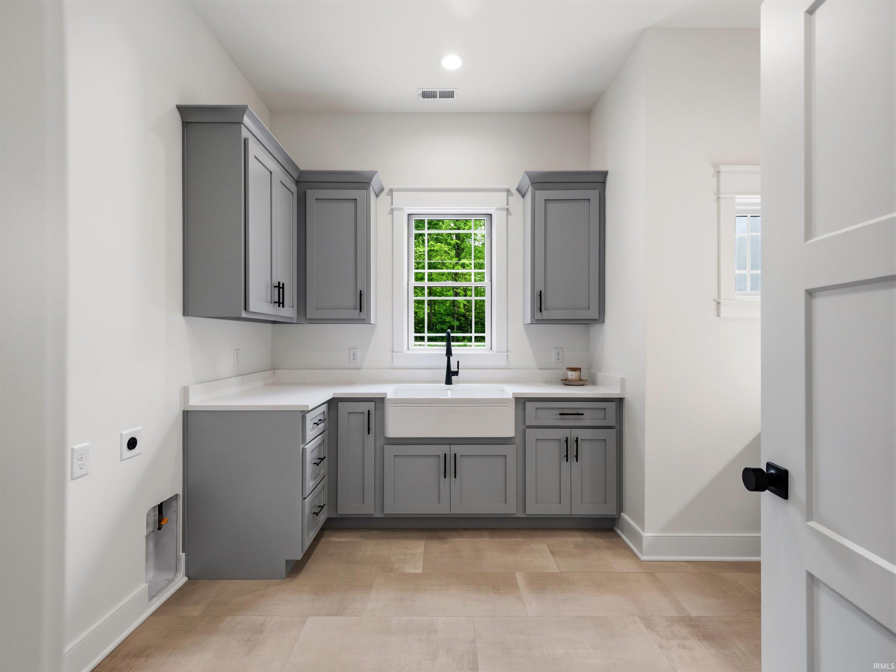 Laundry room featuring light gray cabinetry, white countertops, and wood-finish flooring
