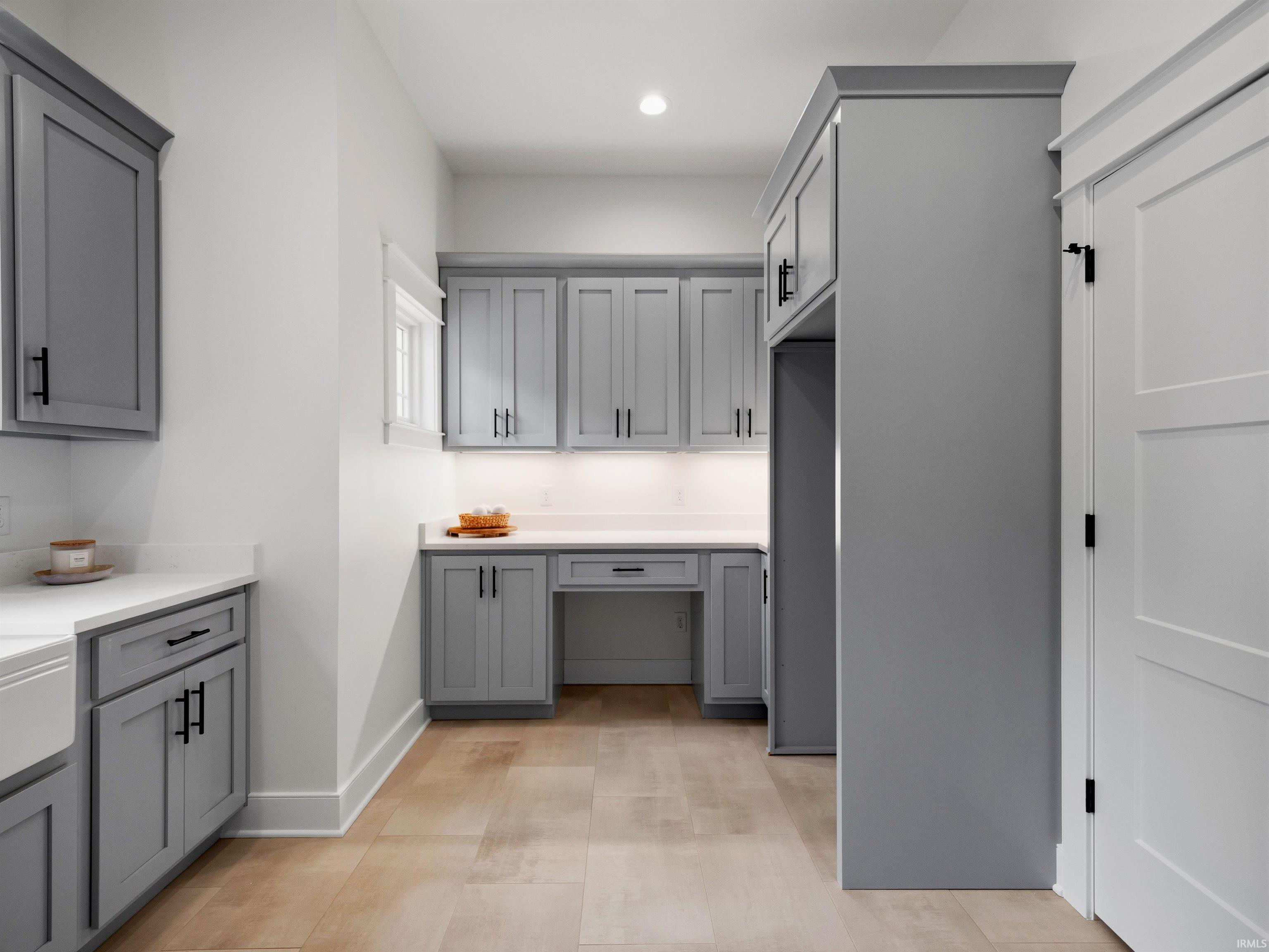 Modern kitchen featuring light gray shaker-style cabinetry, white countertops, and wood-finish flooring