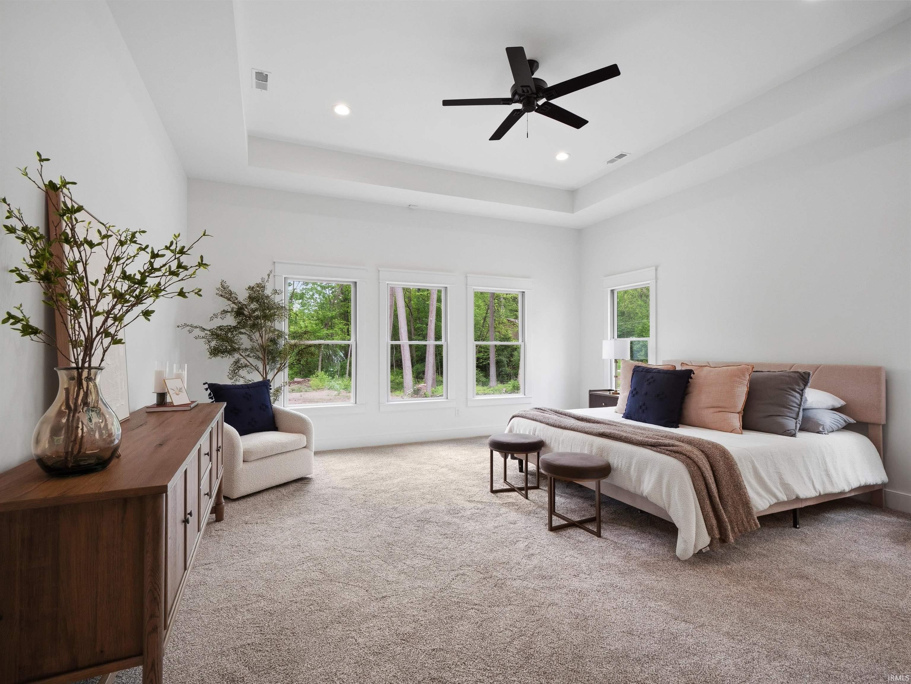 Spacious room featuring a tray ceiling with a black ceiling fan, recessed lighting, and multiple windows