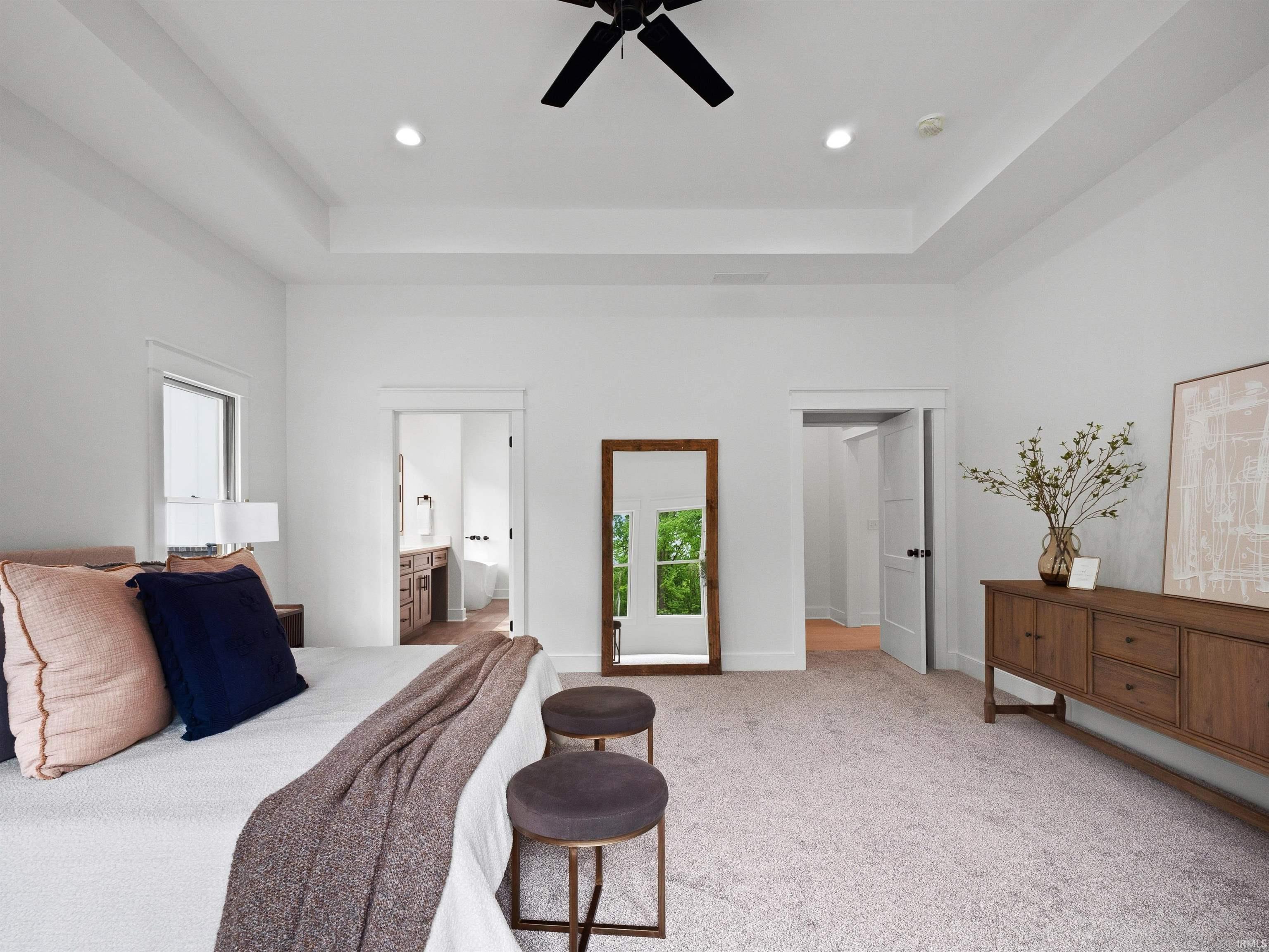 Spacious room featuring a tray ceiling with recessed lighting and a ceiling fan