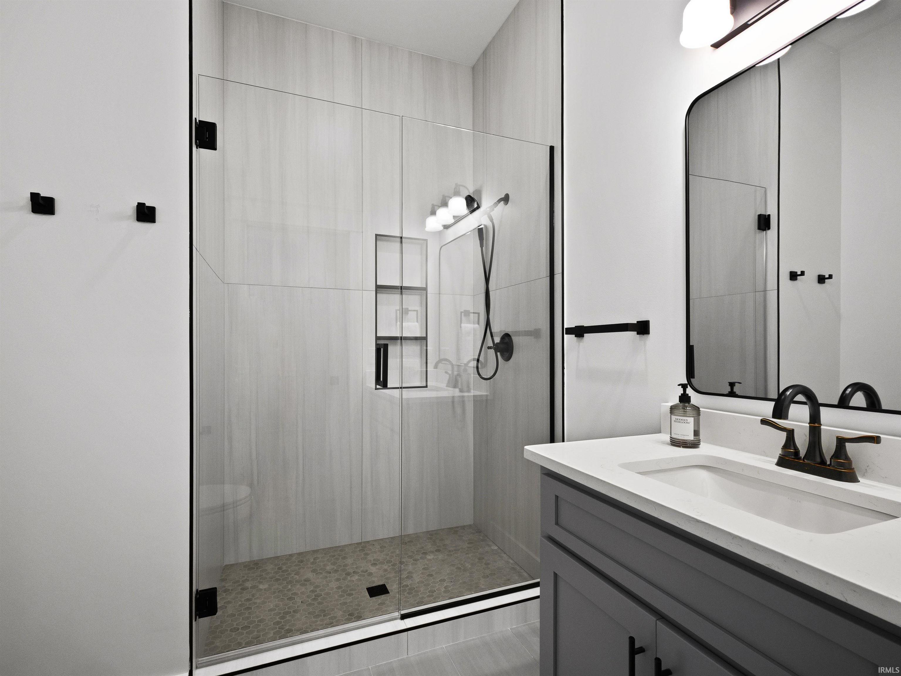 Modern bathroom featuring a frameless glass shower enclosure with matte black hardware