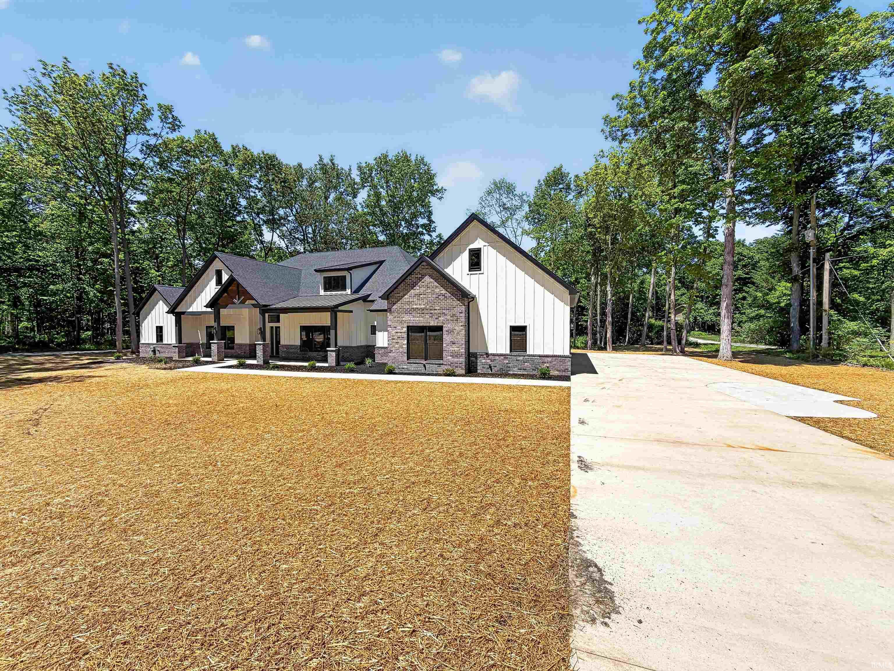 Modern farmhouse exterior featuring board-and-batten siding, stone accents, dark-framed windows, a covered front entry, and an asphalt shingle roof
