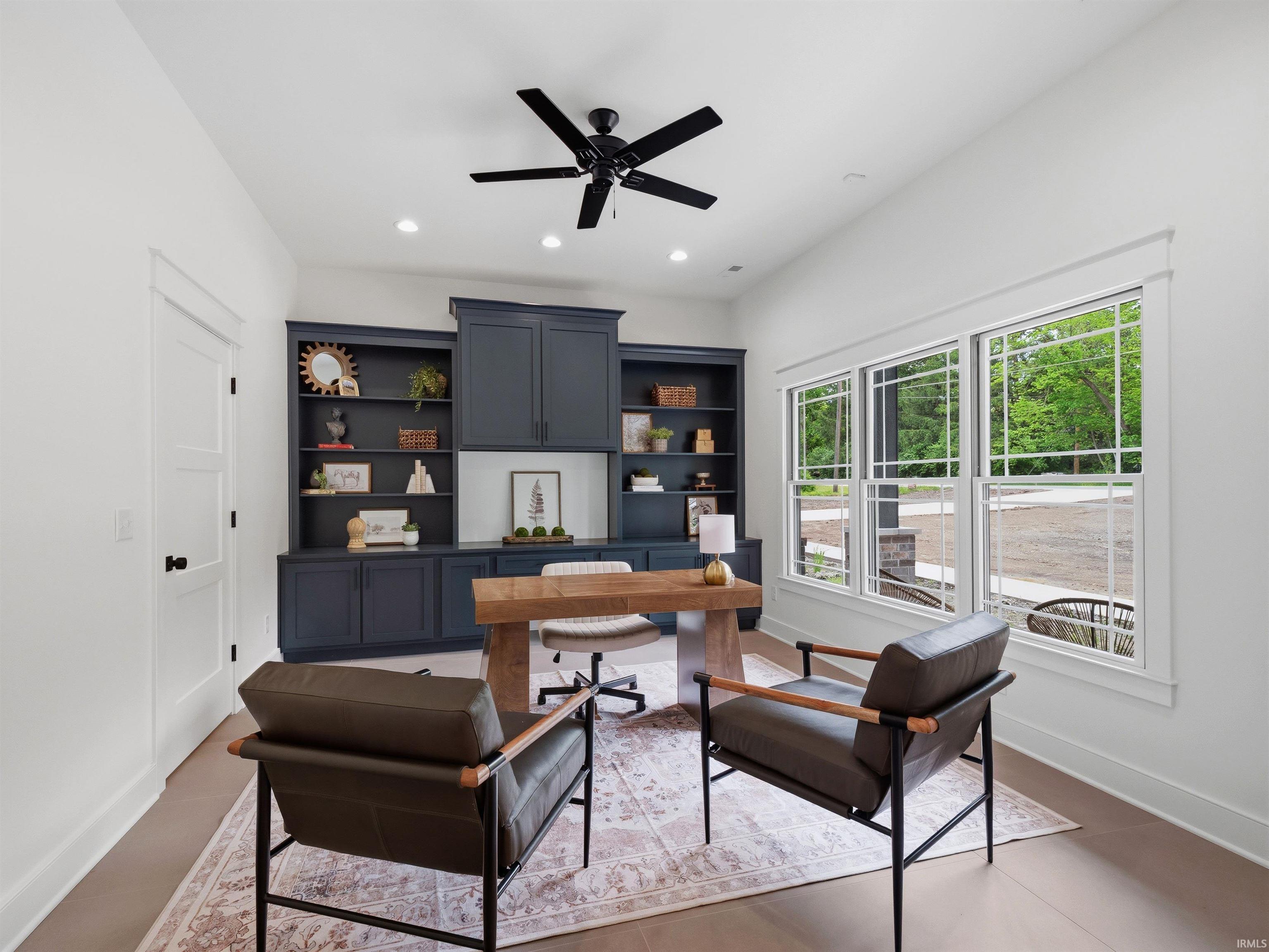 Home office featuring built-in navy cabinetry, a wood-finish desk, and large multi-pane windows