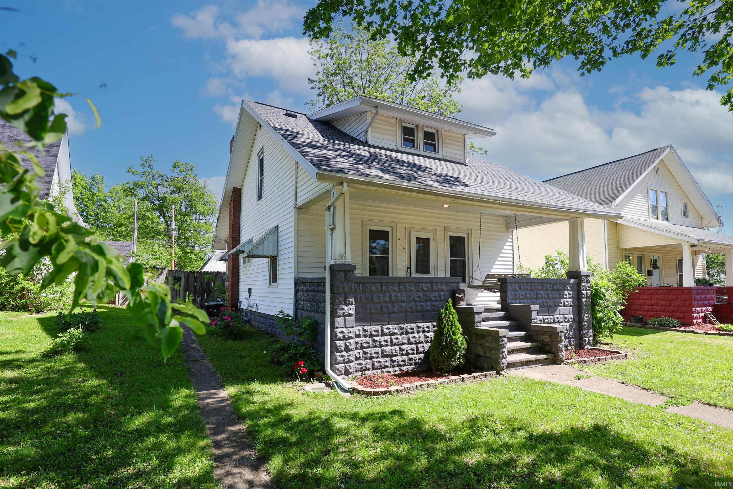 Front exterior featuring white siding, a covered porch, a patterned block foundation, and a gabled roof
