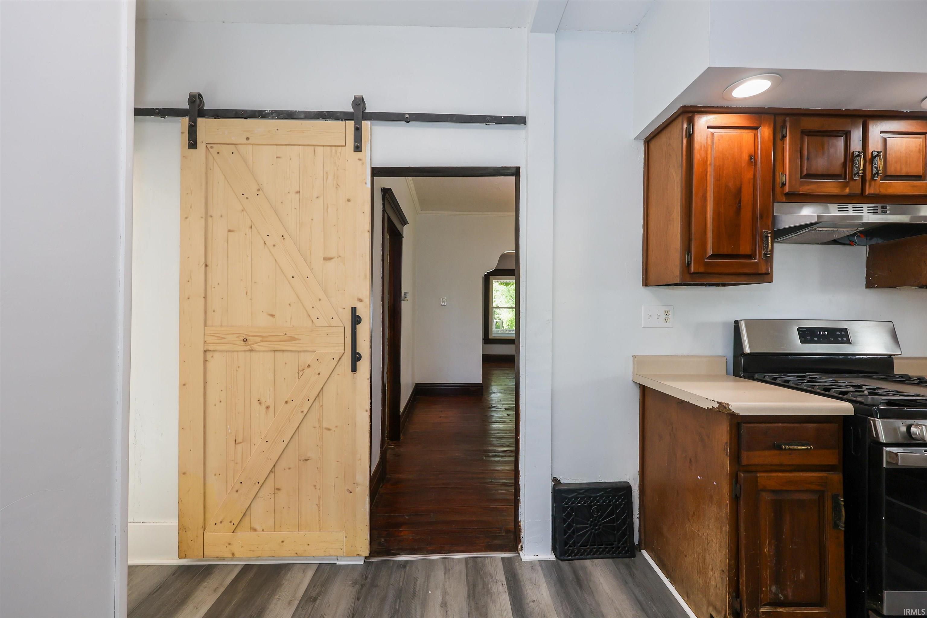 Natural wood-tone barn door with black hardware, complementing wood-finish flooring