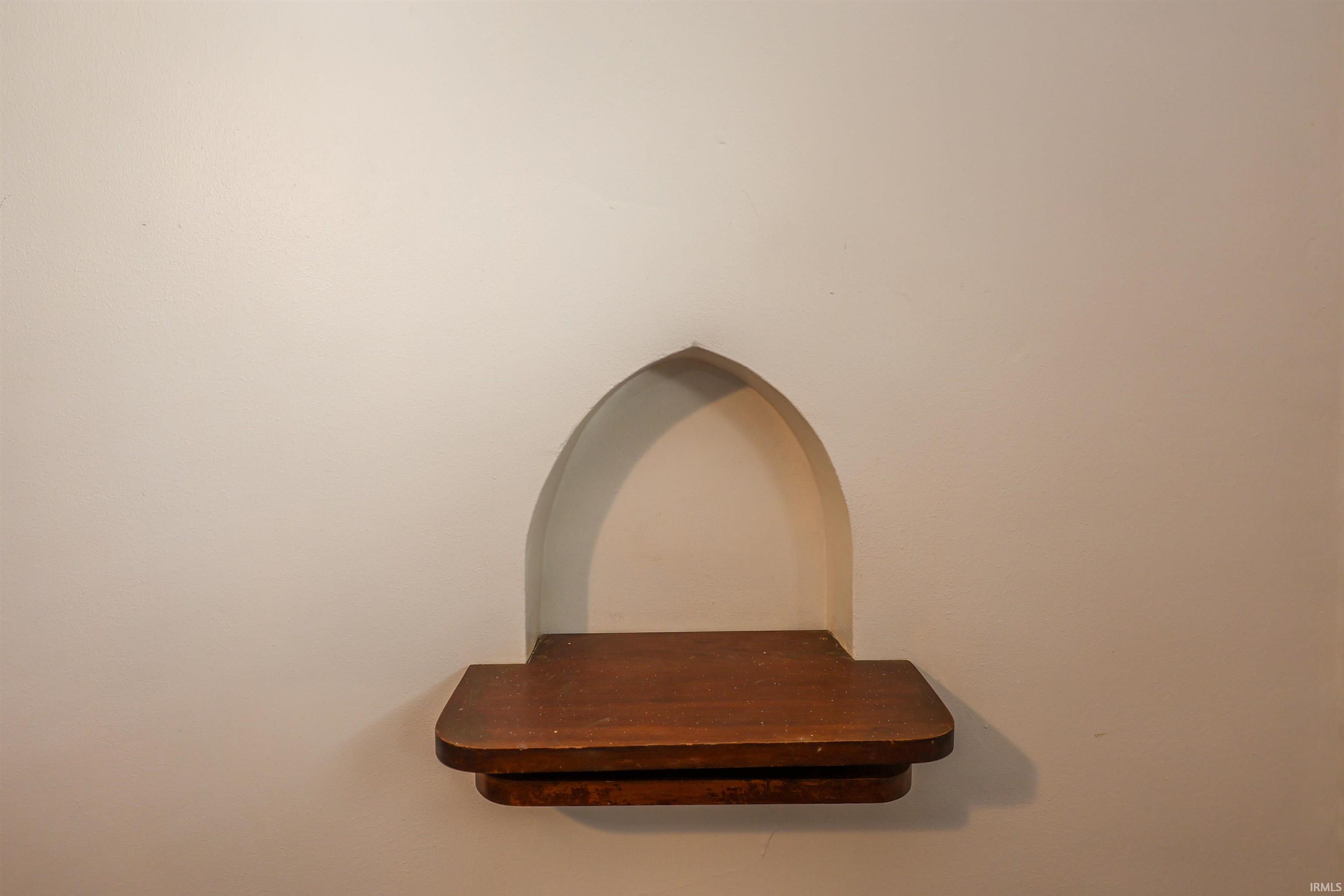 Arch-top wall niche with a dark wood-finish shelf