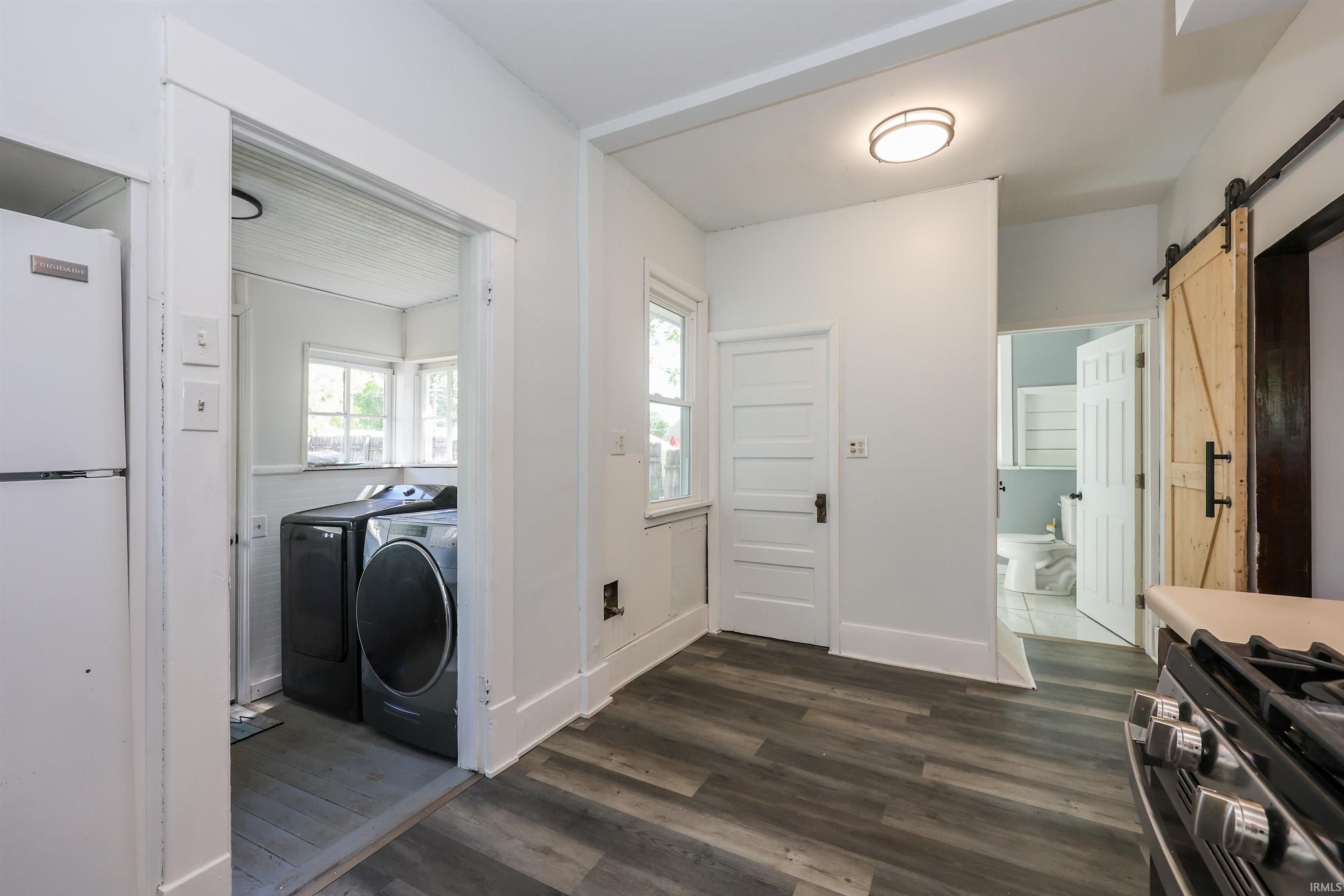 Interior space featuring wood-finish flooring, white walls, and a barn door