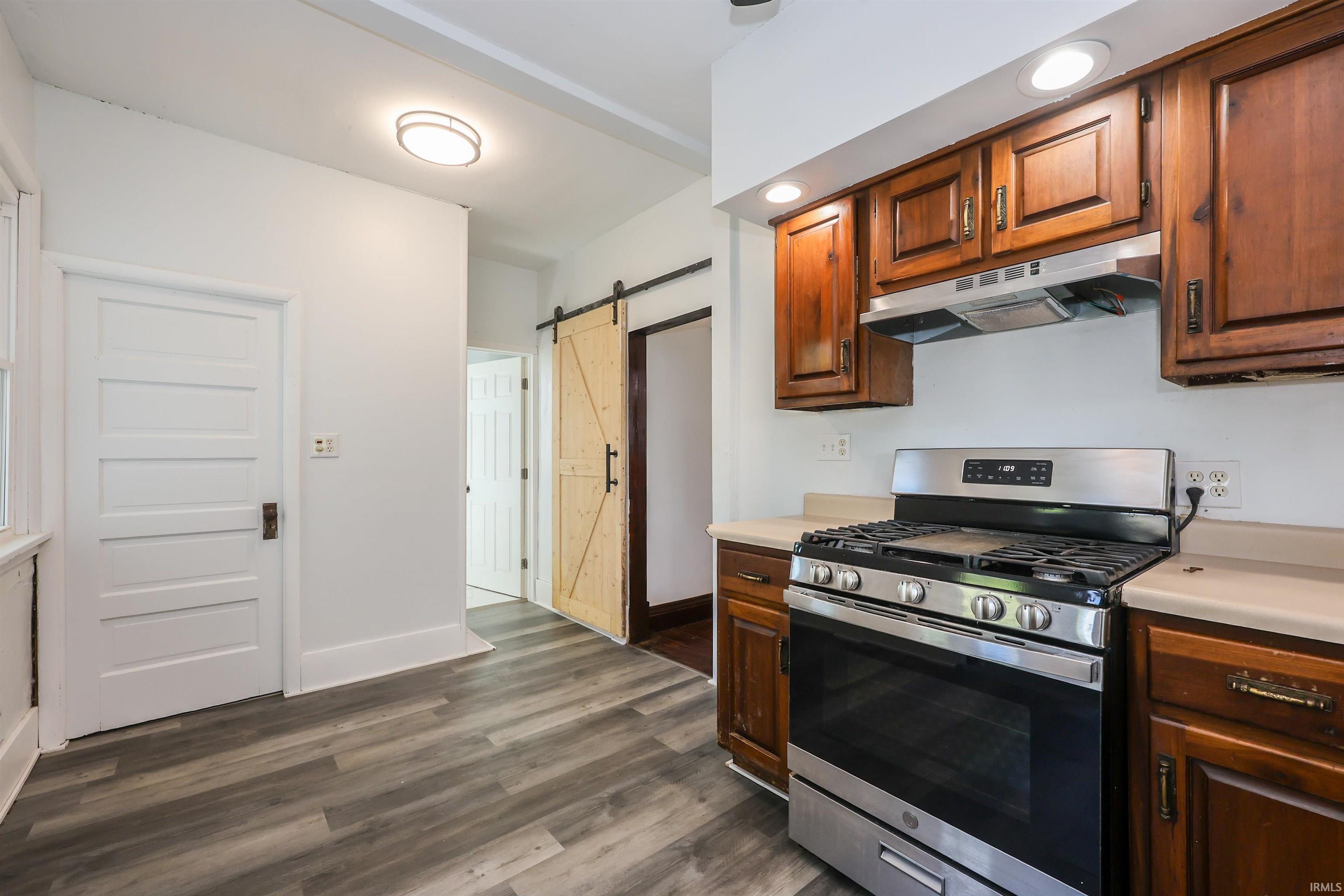 Modern kitchen featuring wood-finish flooring, a stainless steel range with overhead ventilation, and recessed lighting