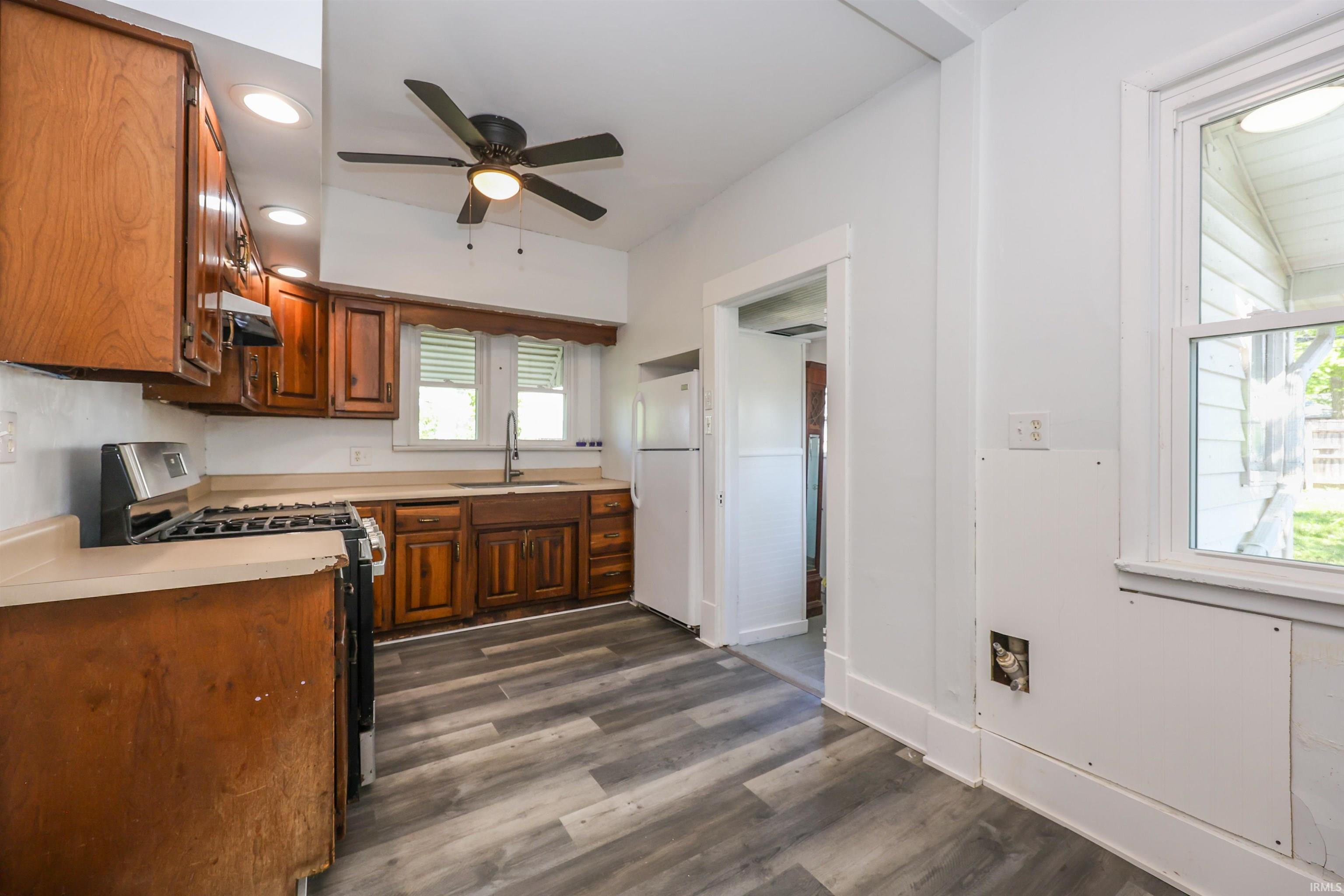 Kitchen featuring wood cabinetry, laminate countertops, a stainless steel range, and wood-finish flooring