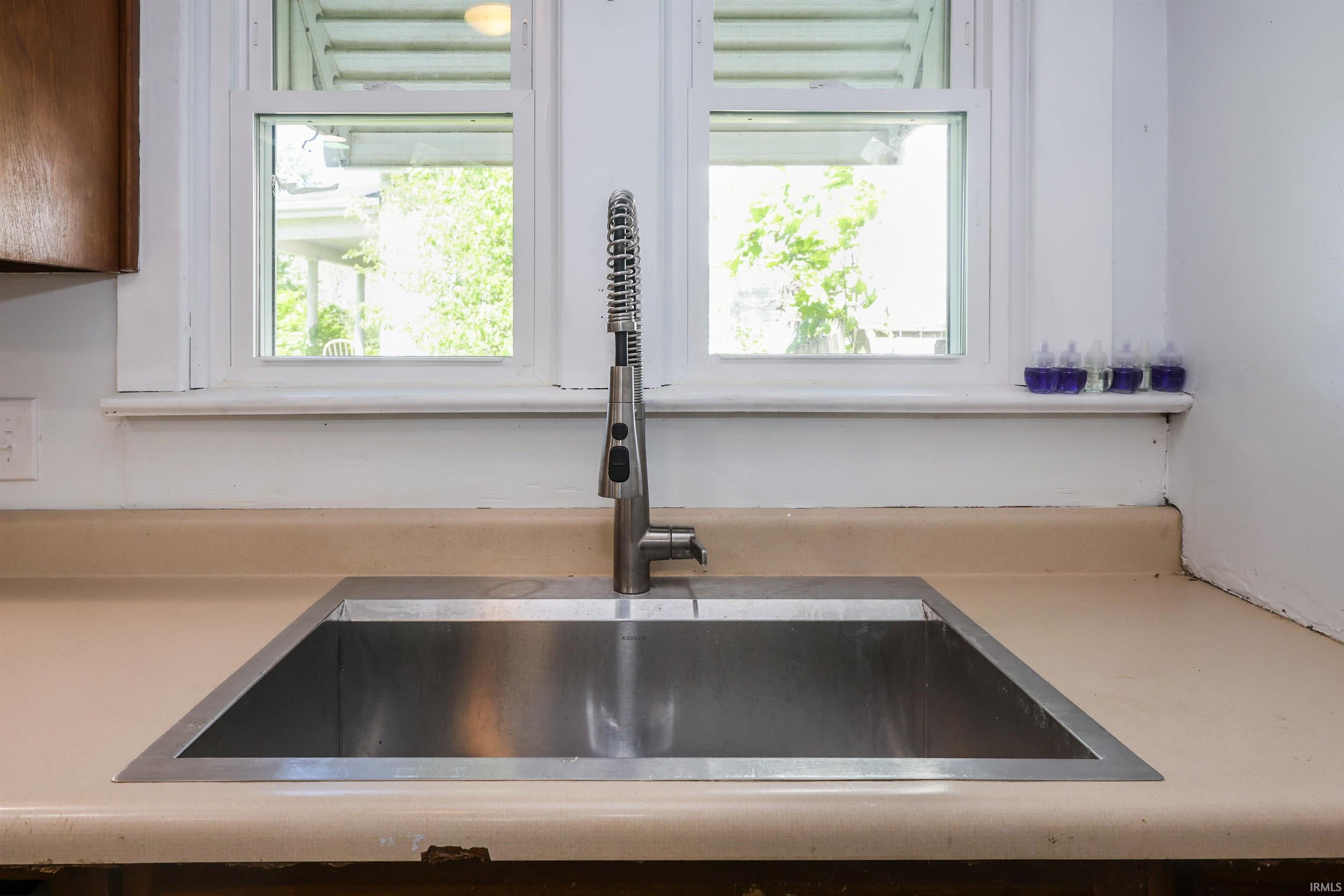 Stainless steel undermount sink with a modern pull-down faucet, set into a neutral-toned countertop