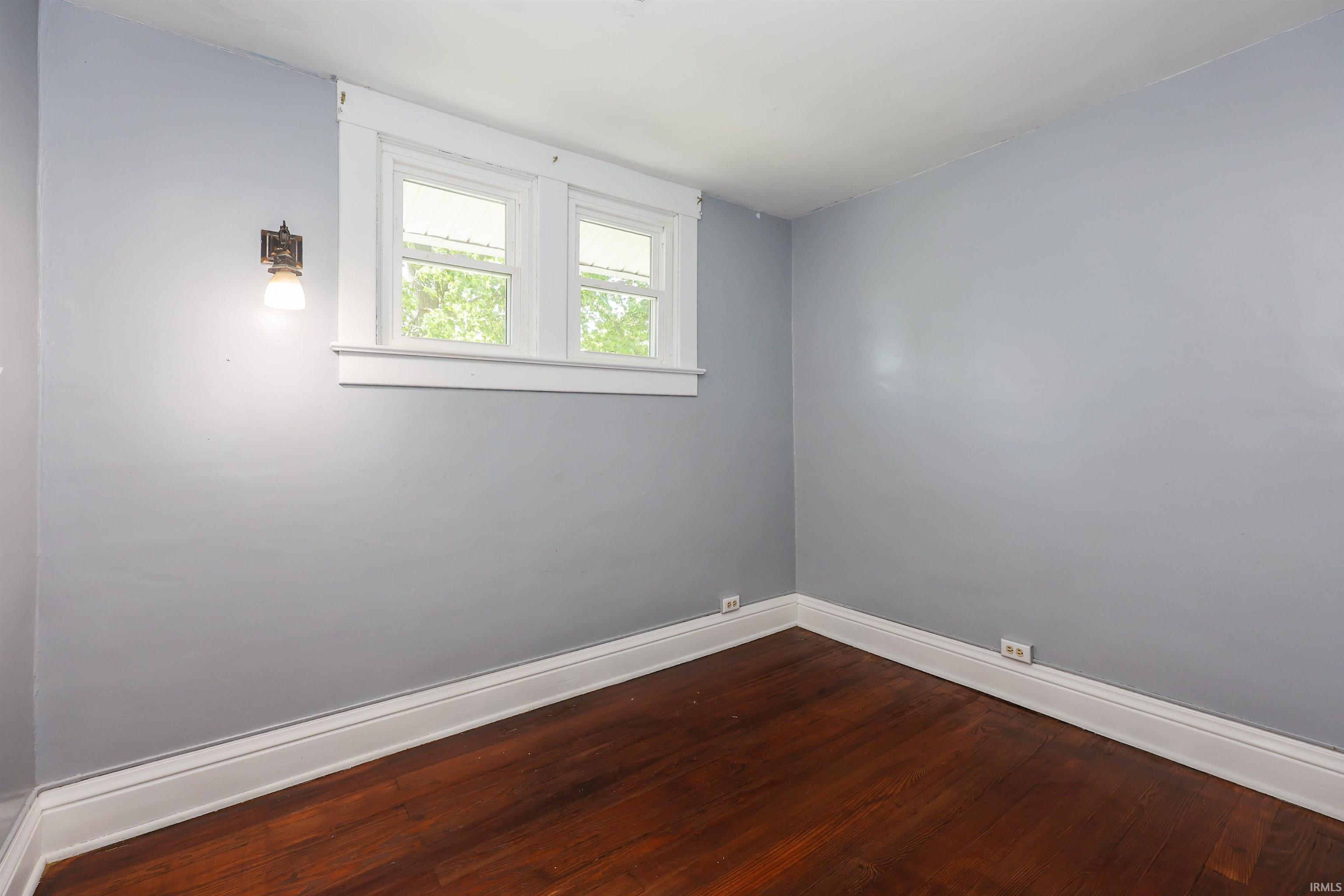 Interior room featuring rich wood-finish flooring, light grey wall paint, and white trim