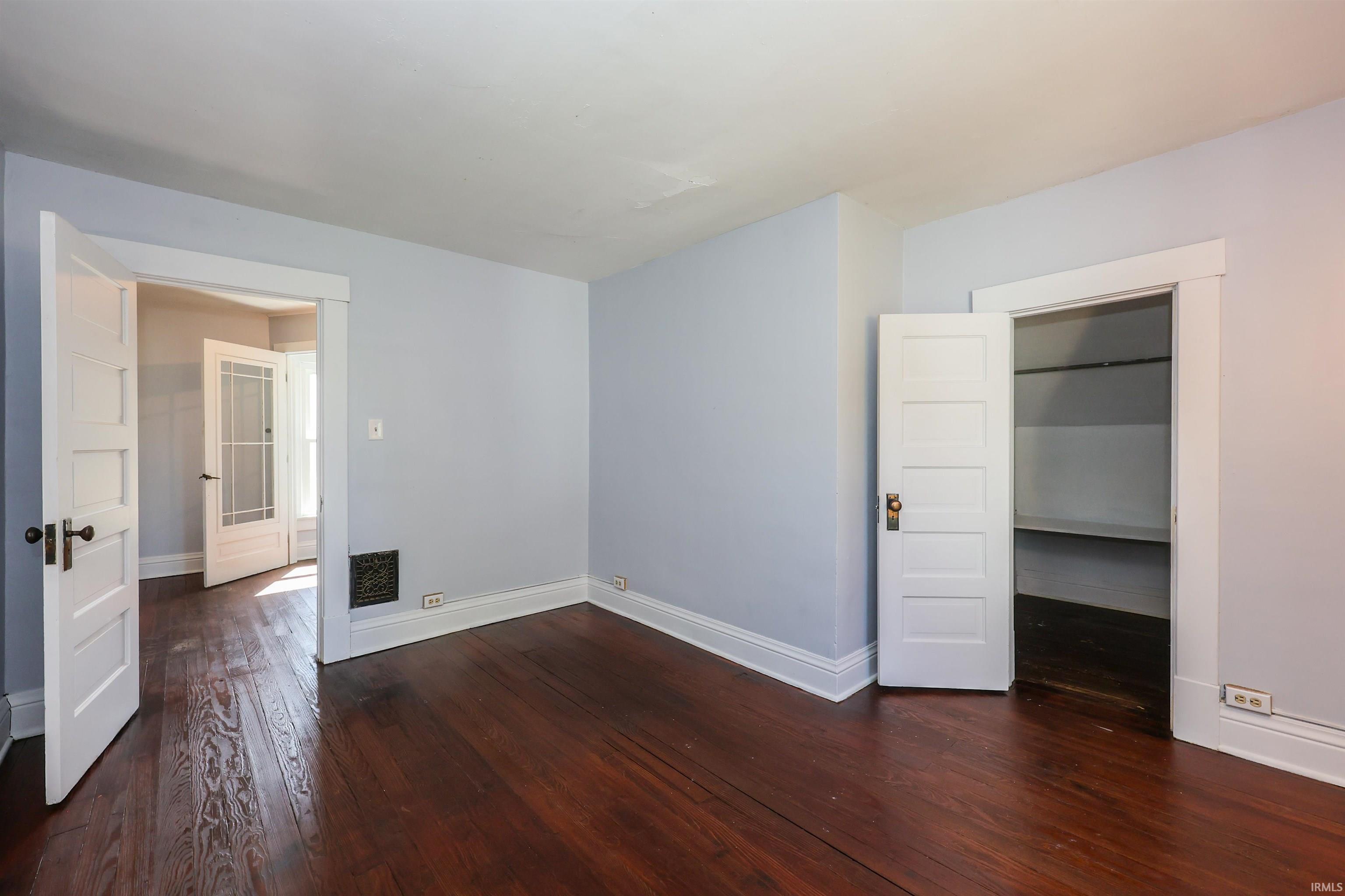 Hardwood flooring throughout, white baseboards, and light blue wall paint