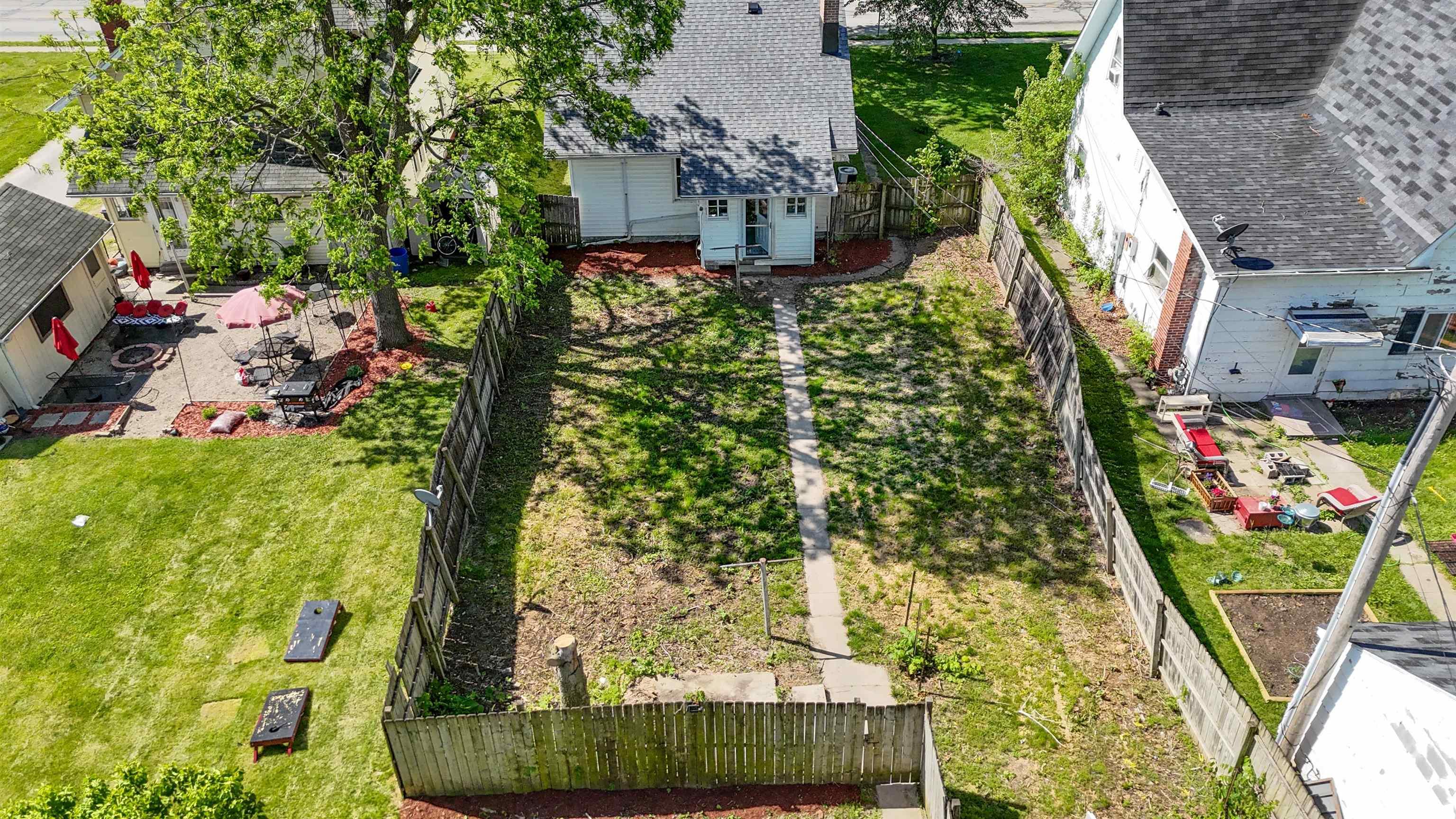 Expansive backyard featuring a concrete pathway, a wooden privacy fence, and a green lawn area