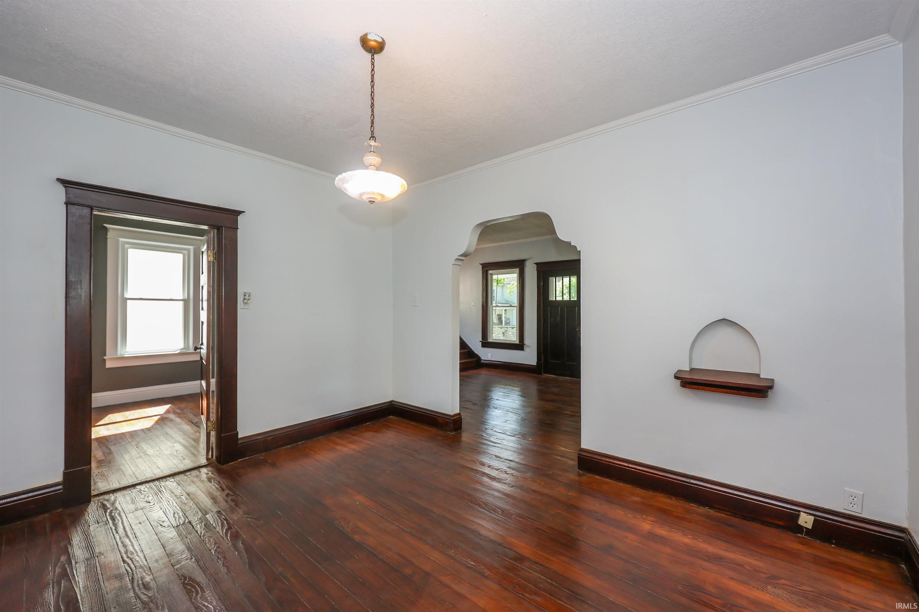 Hardwood flooring throughout, featuring dark wood trim, a decorative wall niche, and an ornate pendant light fixture