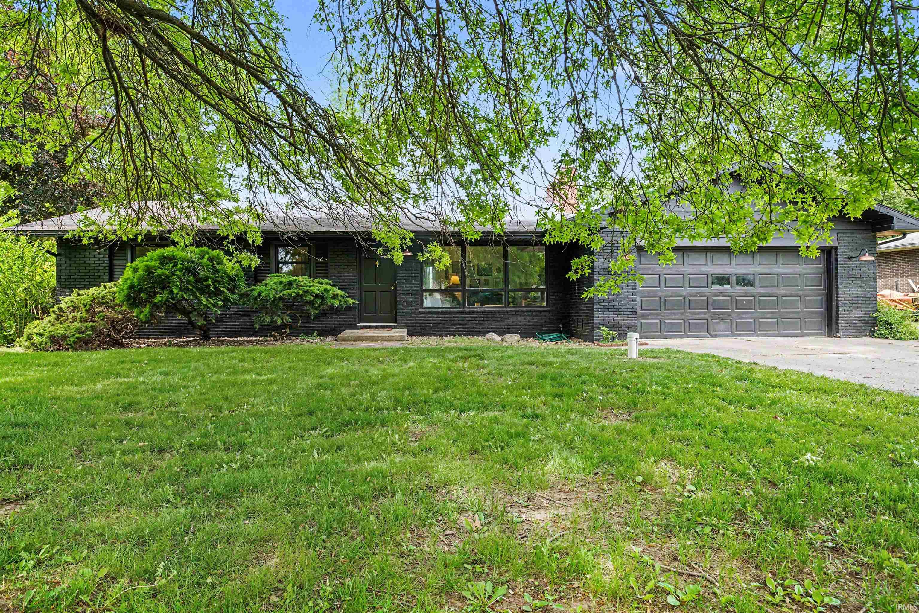 Dark brick exterior featuring a multi-pane garage door, front entry with stone steps, and a large picture window