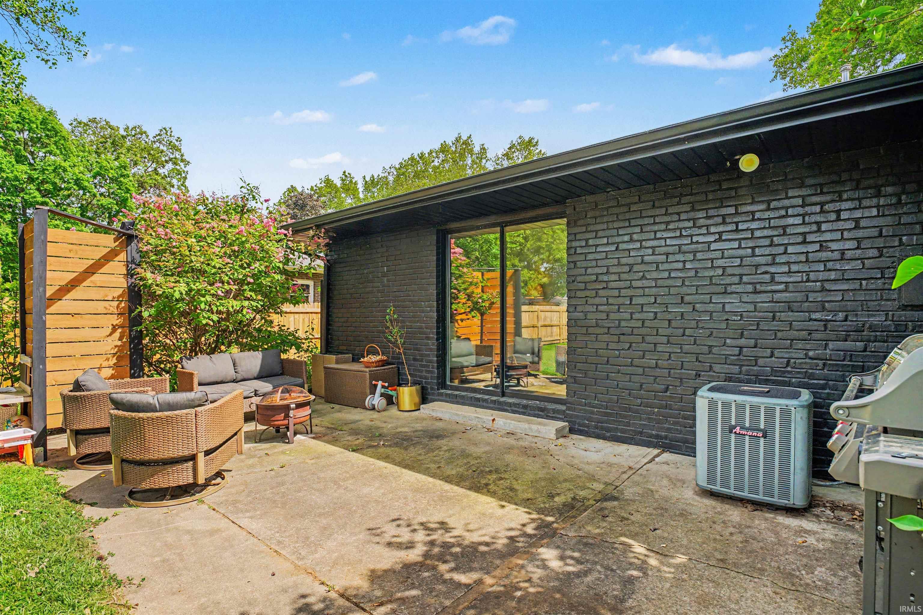 Concrete patio with a black brick exterior wall and a large picture window