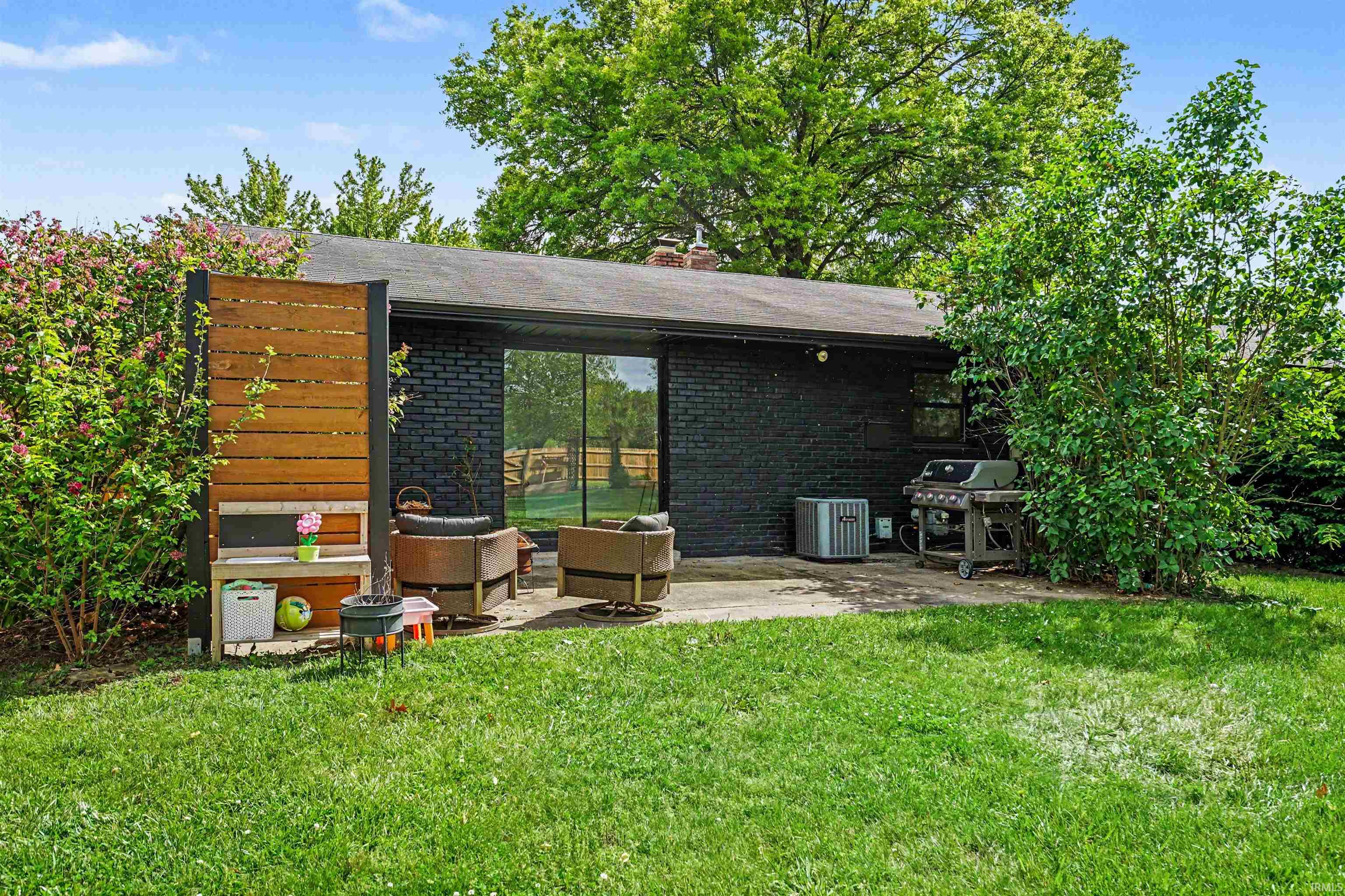 Private patio space featuring a black brick exterior, large sliding glass door, and adjacent wooden privacy screen