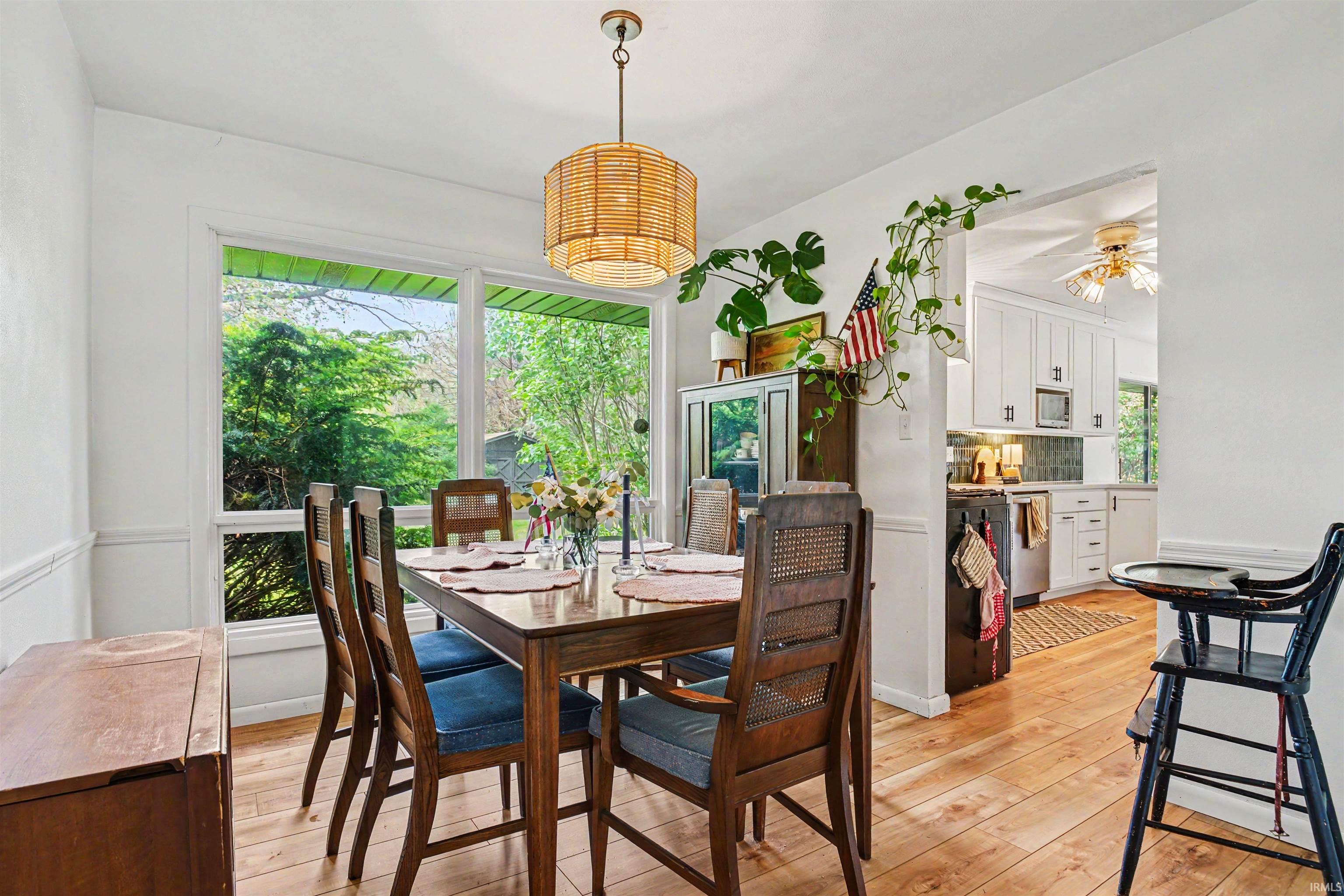 Dining space featuring wood-finish flooring, a wall of windows, and a woven pendant light fixture
