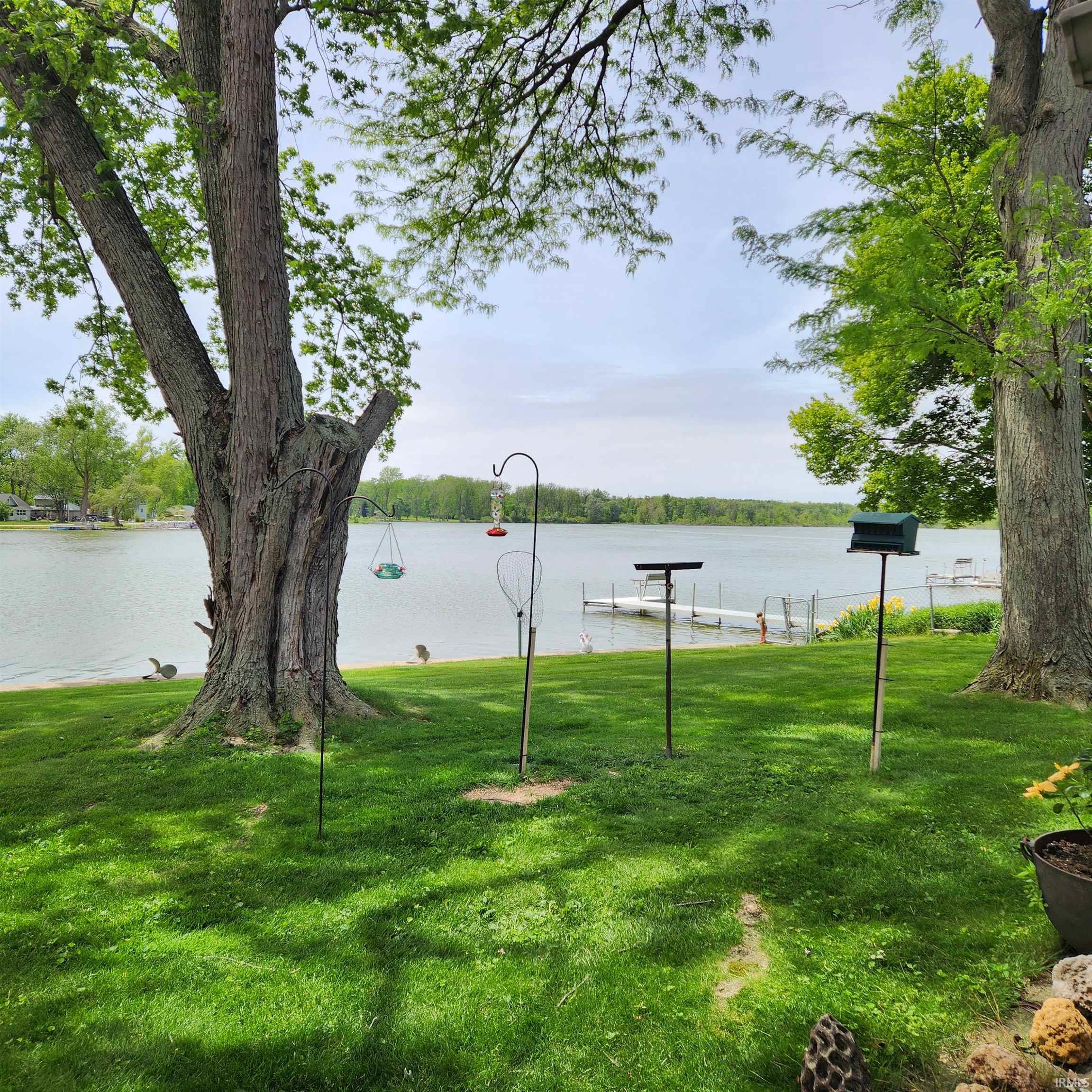 Expansive waterfront lawn featuring mature trees and direct lake access