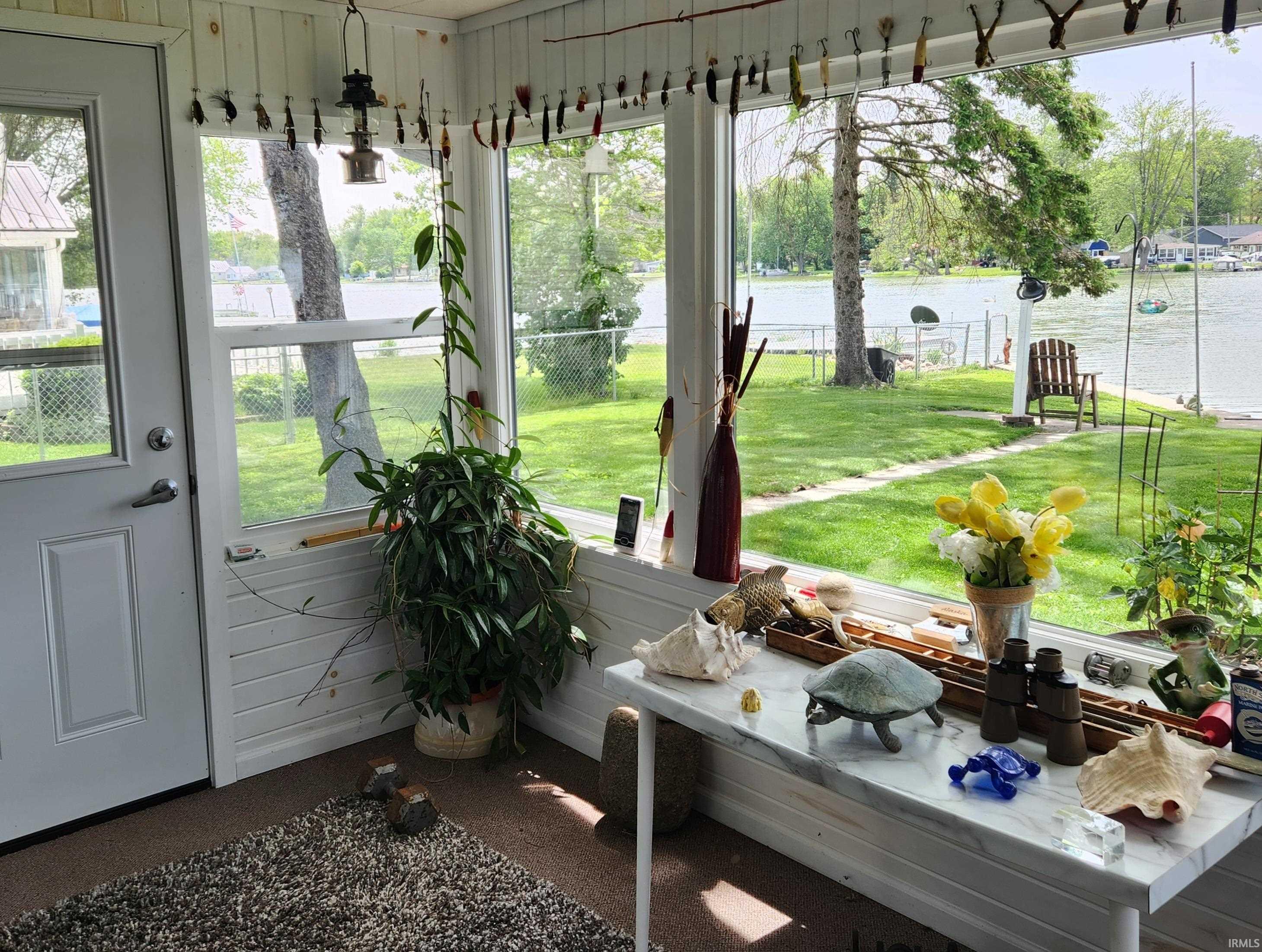 Sunroom featuring white paneled walls, a single exterior door with a glass insert, and large windows overlooking a body of water