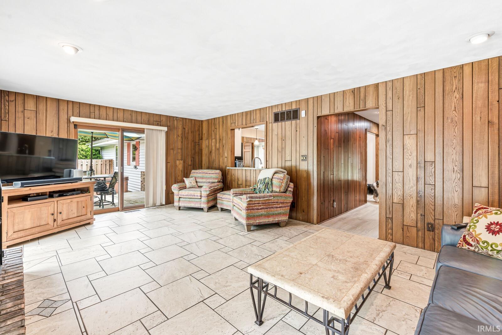Spacious room featuring wood-panel walls and light-toned tile flooring with geometric patterns