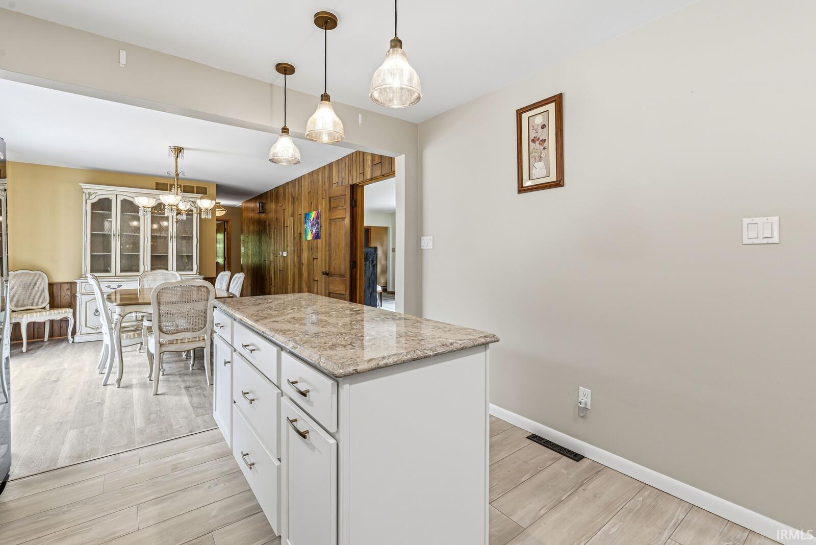 Kitchen island featuring a stone-finish countertop with pendant lighting above