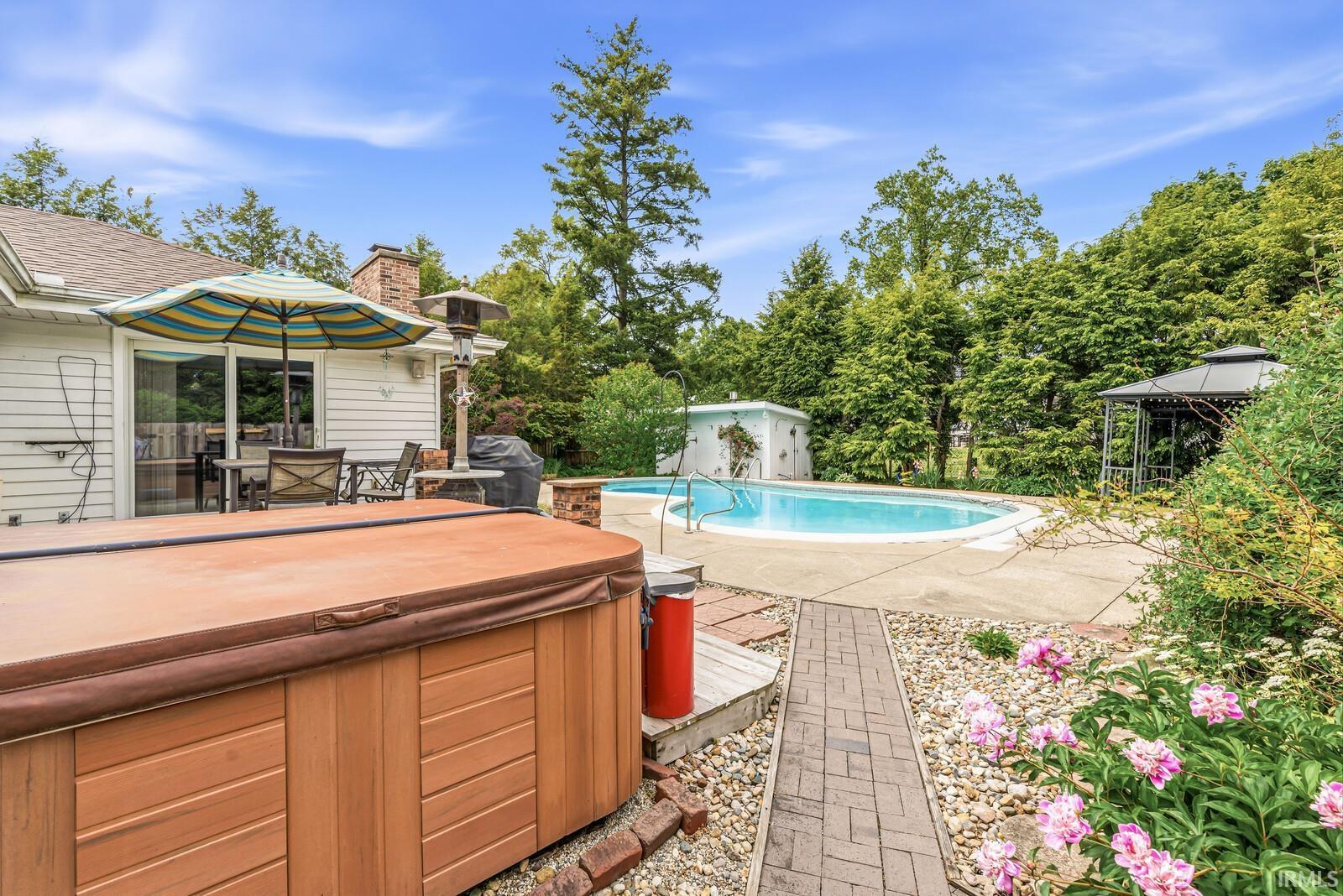 Expansive backyard featuring an inground swimming pool, hot tub, and a decorative gazebo
