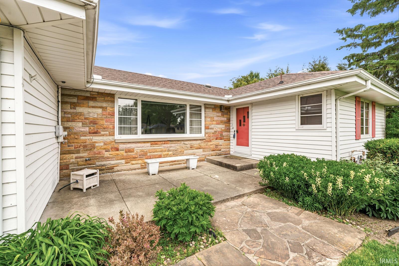Split-level exterior featuring white siding and natural stone accents