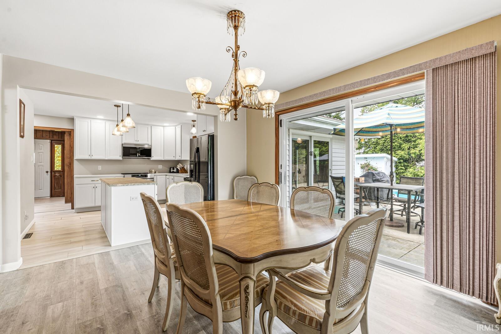 Dining area featuring light wood-finish flooring and a brass chandelier