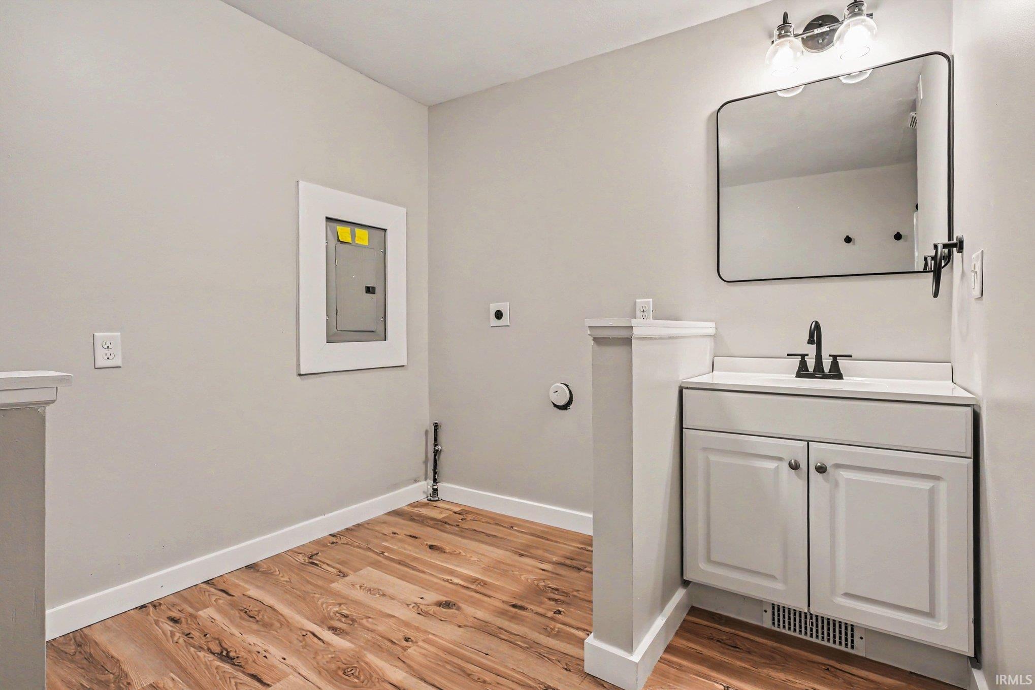 White vanity with integrated sink, black faucet, and rectangular mirror