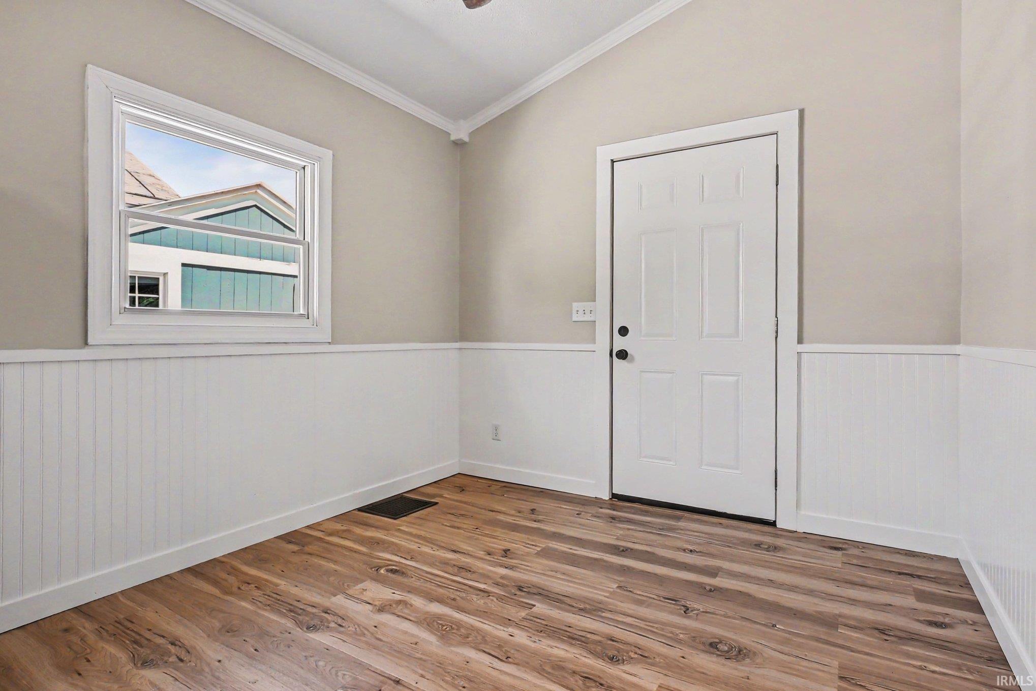 Interior space featuring wood-finish flooring, white paneled wainscoting, and neutral-toned walls