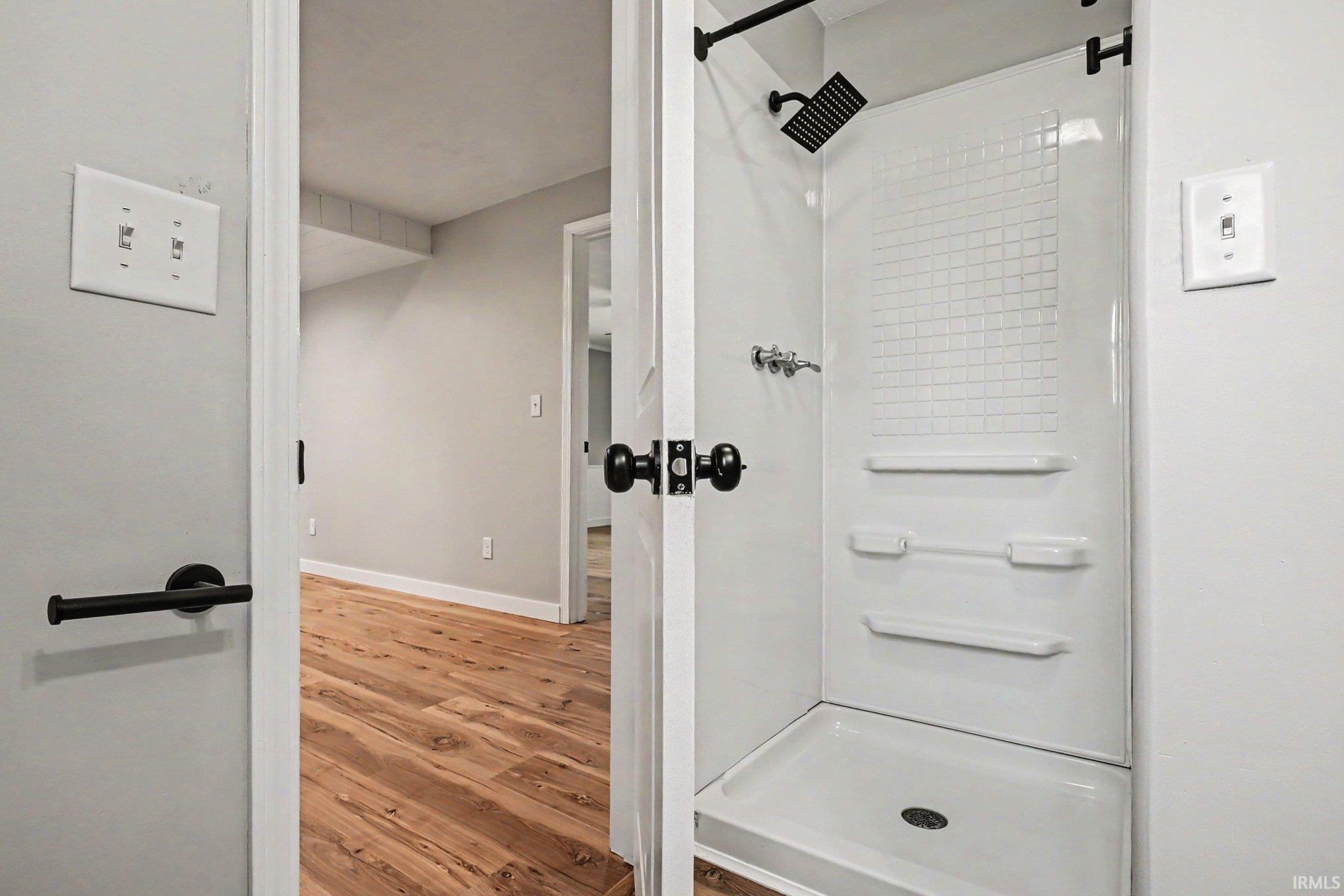 White shower stall with integrated shelving, rainfall shower head, and matte black fixtures