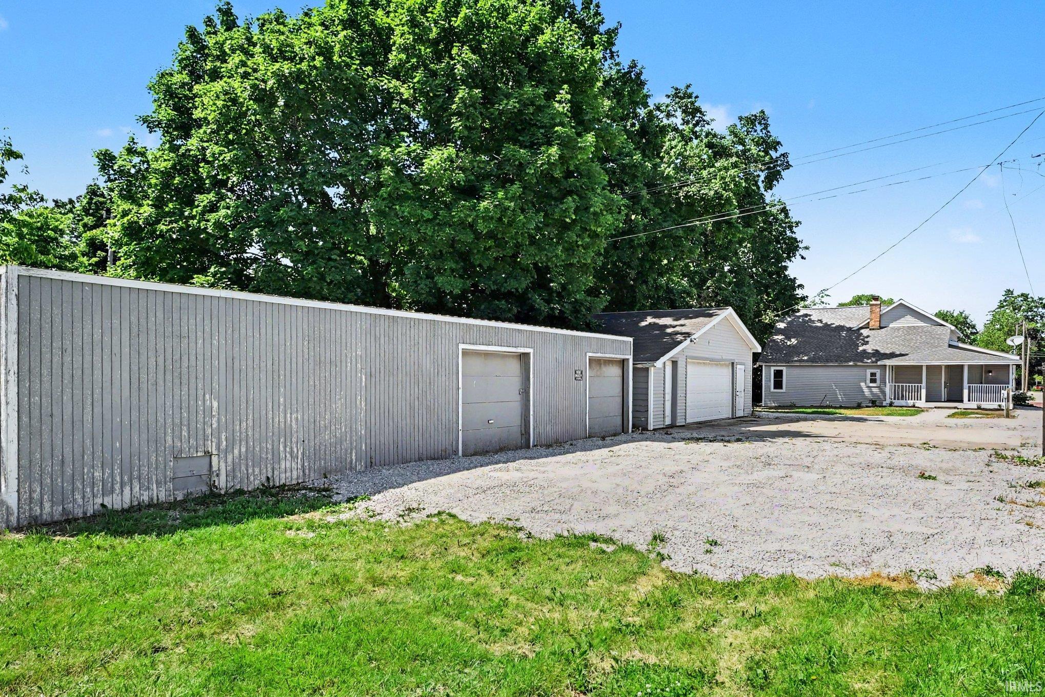 Expansive gravel parking area with a large detached garage structure