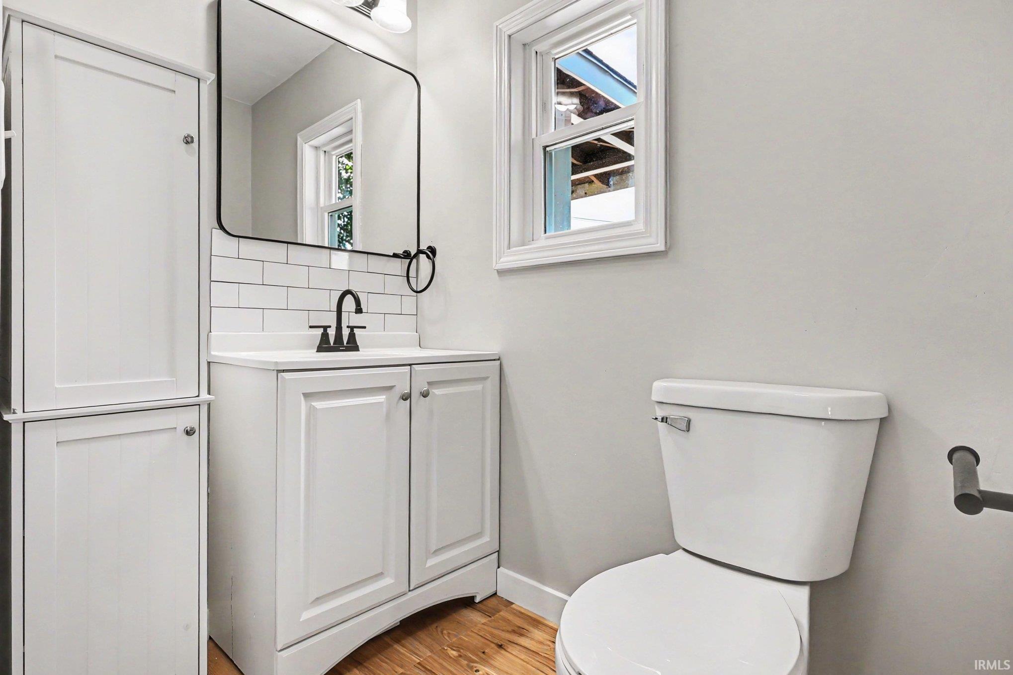 Bathroom featuring a white vanity with a rectangular sink, matte black faucet, and subway tile backsplash