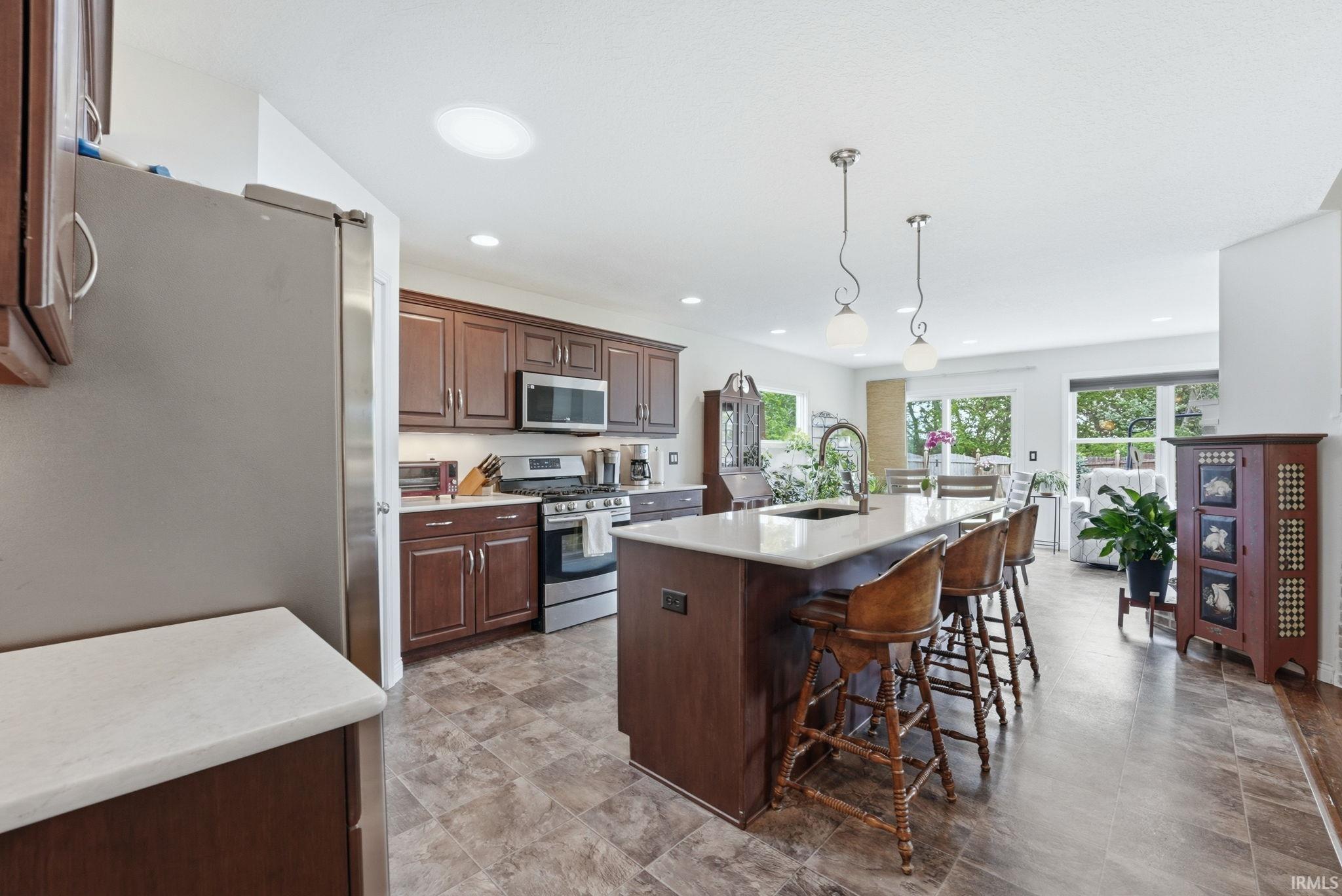 Modern kitchen with an integrated island featuring counter seating, a stainless steel sink, and pendant lighting