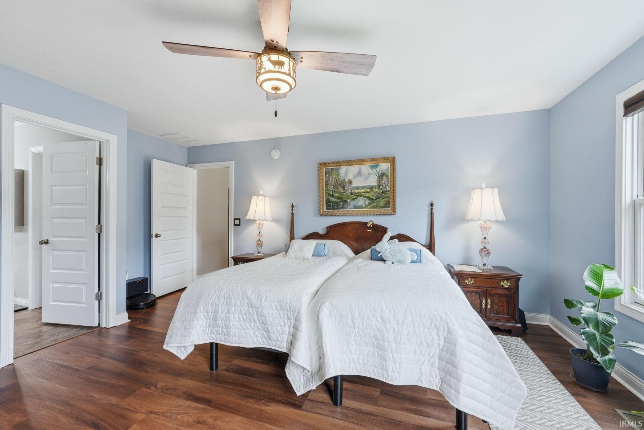 Spacious room featuring wood-finish flooring, light blue walls, and a ceiling fan with integrated lighting